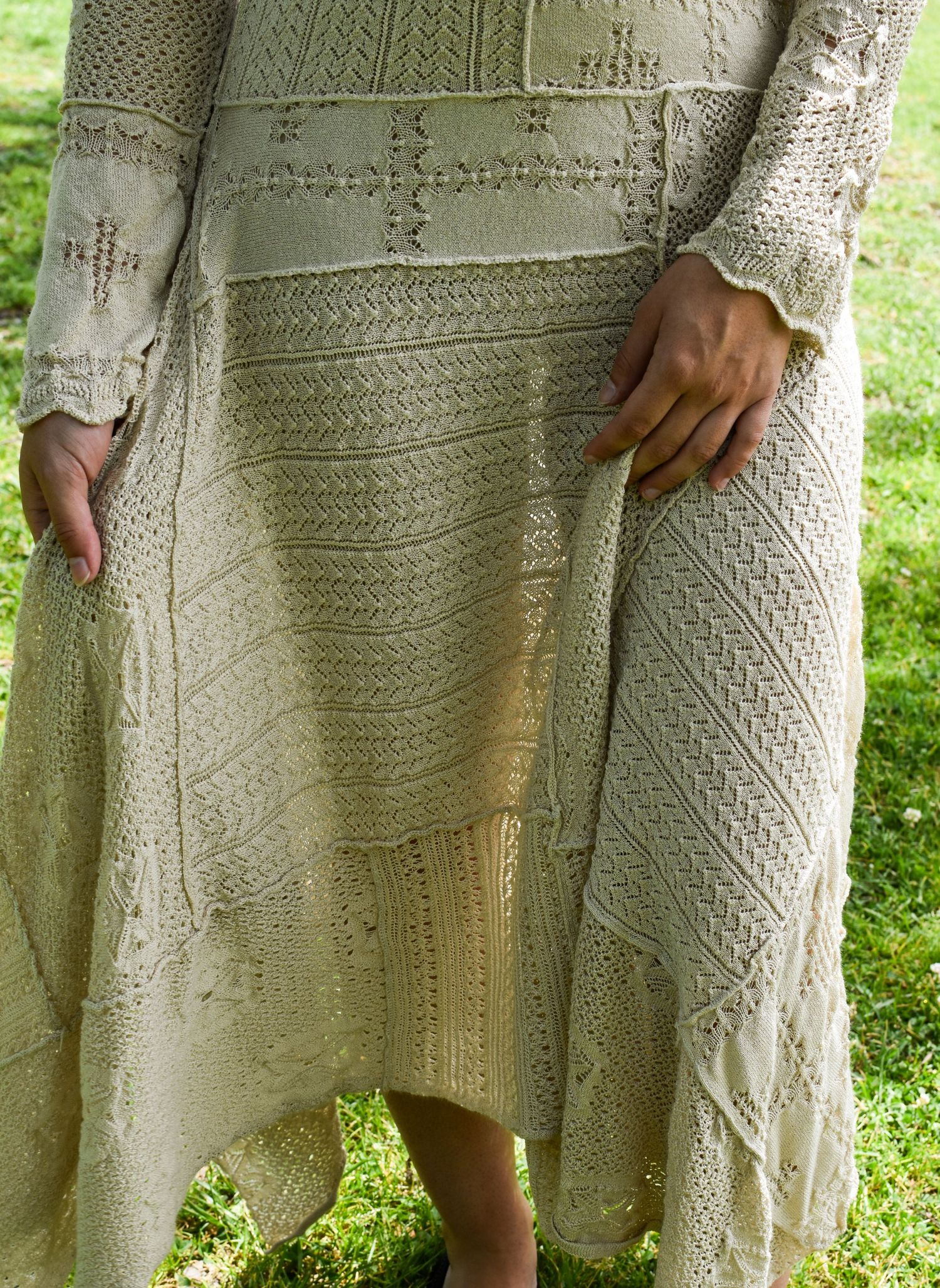 Close-up detail of an intricate cream knit dress with cross pattern detailing.