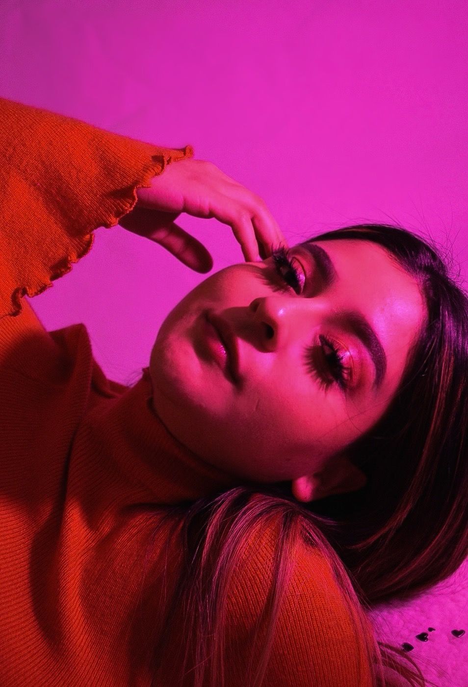 Artistic portrait in magenta lighting with a red sweater creating dramatic shadows and highlights.