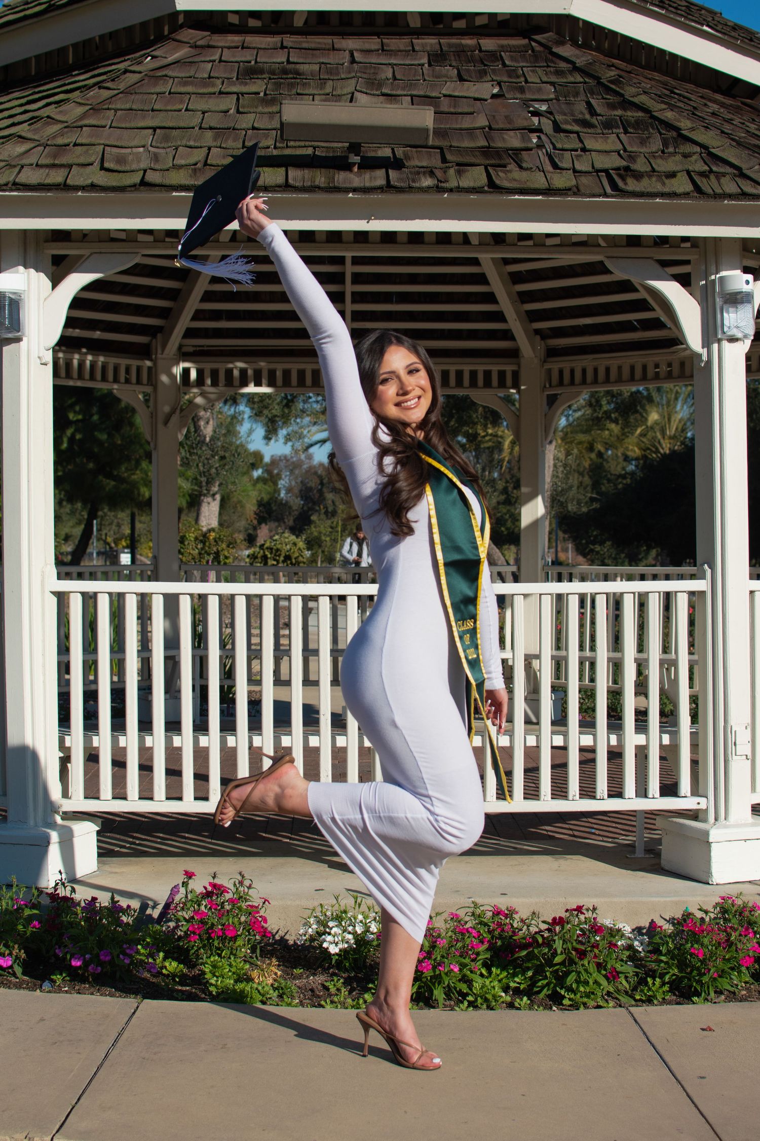 Dance pose performed in front of white gazebo with flowers in the foreground.
