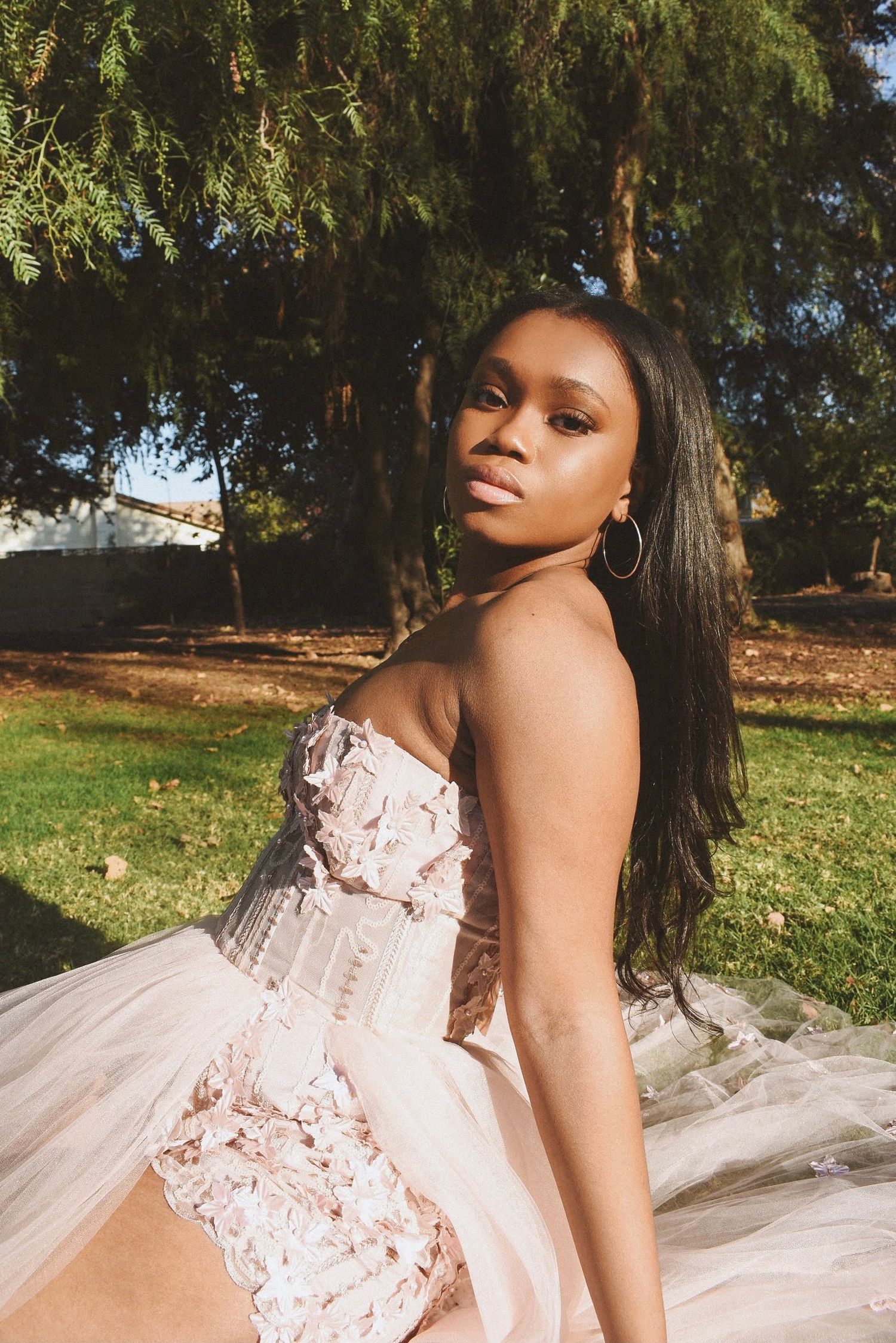An elegant blush tulle gown with lace details photographed in an outdoor garden setting.
