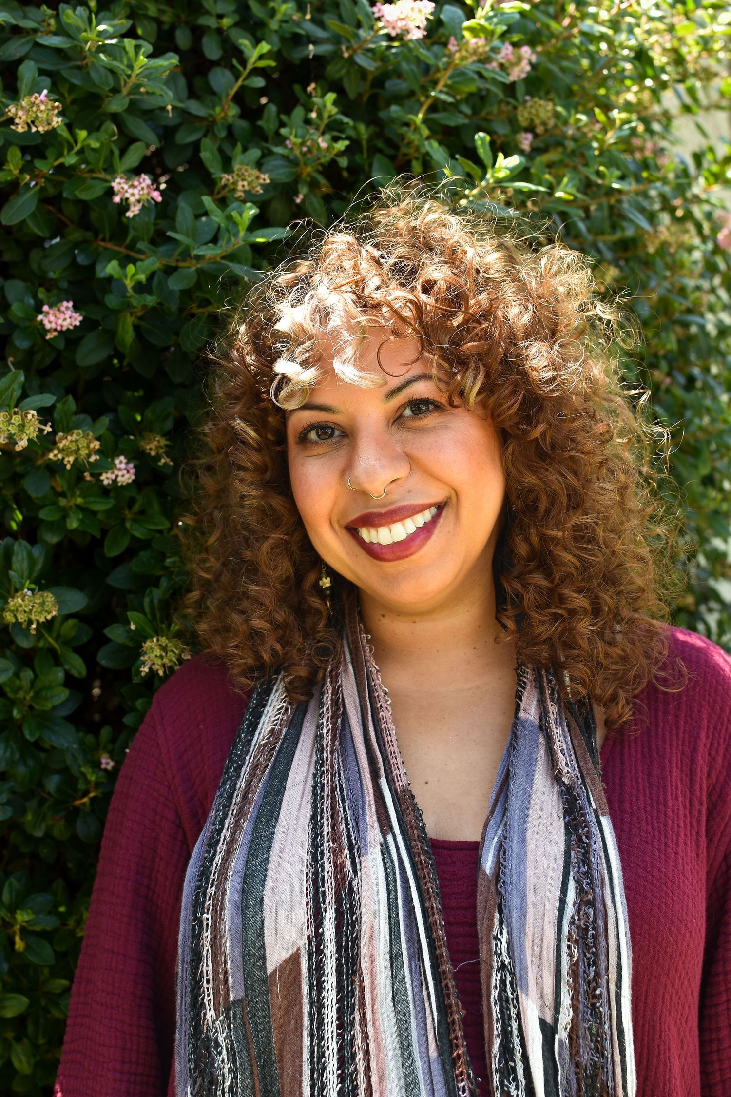 Series of casual portraits showing natural curly hair and striped scarf against green garden setting.