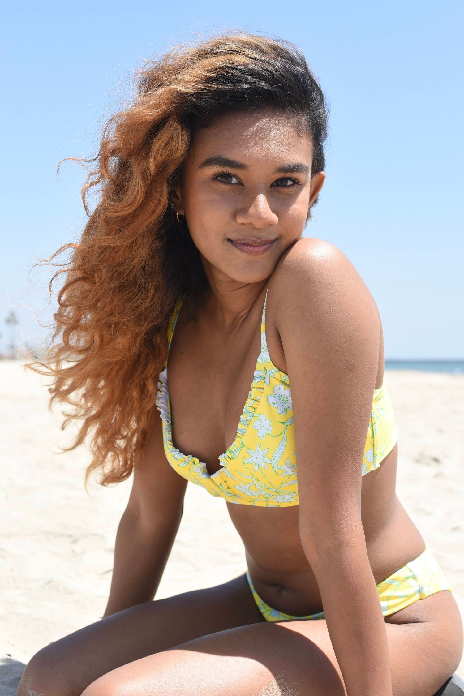 Yellow floral bikini displayed in multiple angles on sunny beach setting.