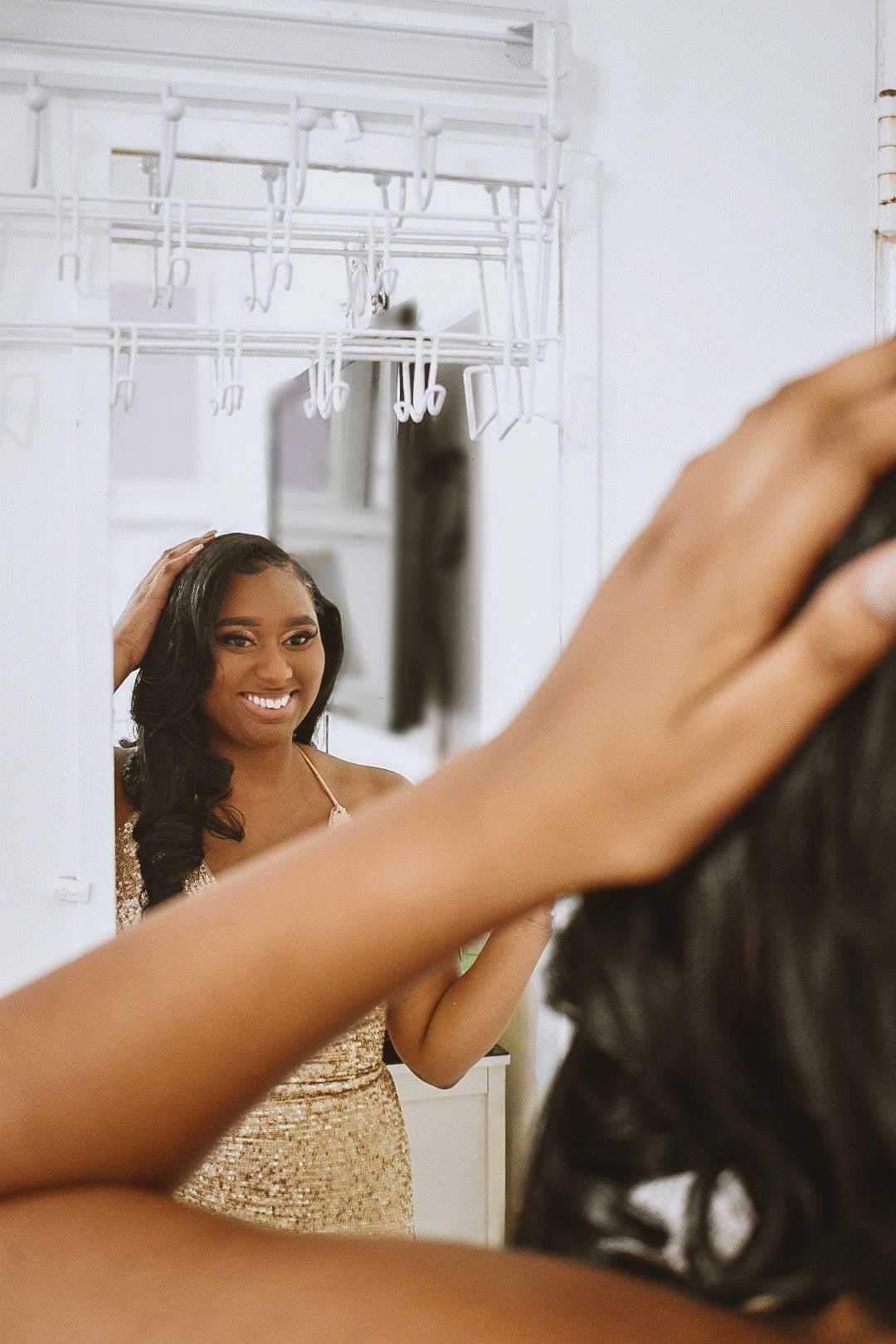 Candid mirror shot showing radiant smile and gold sequined formal dress.