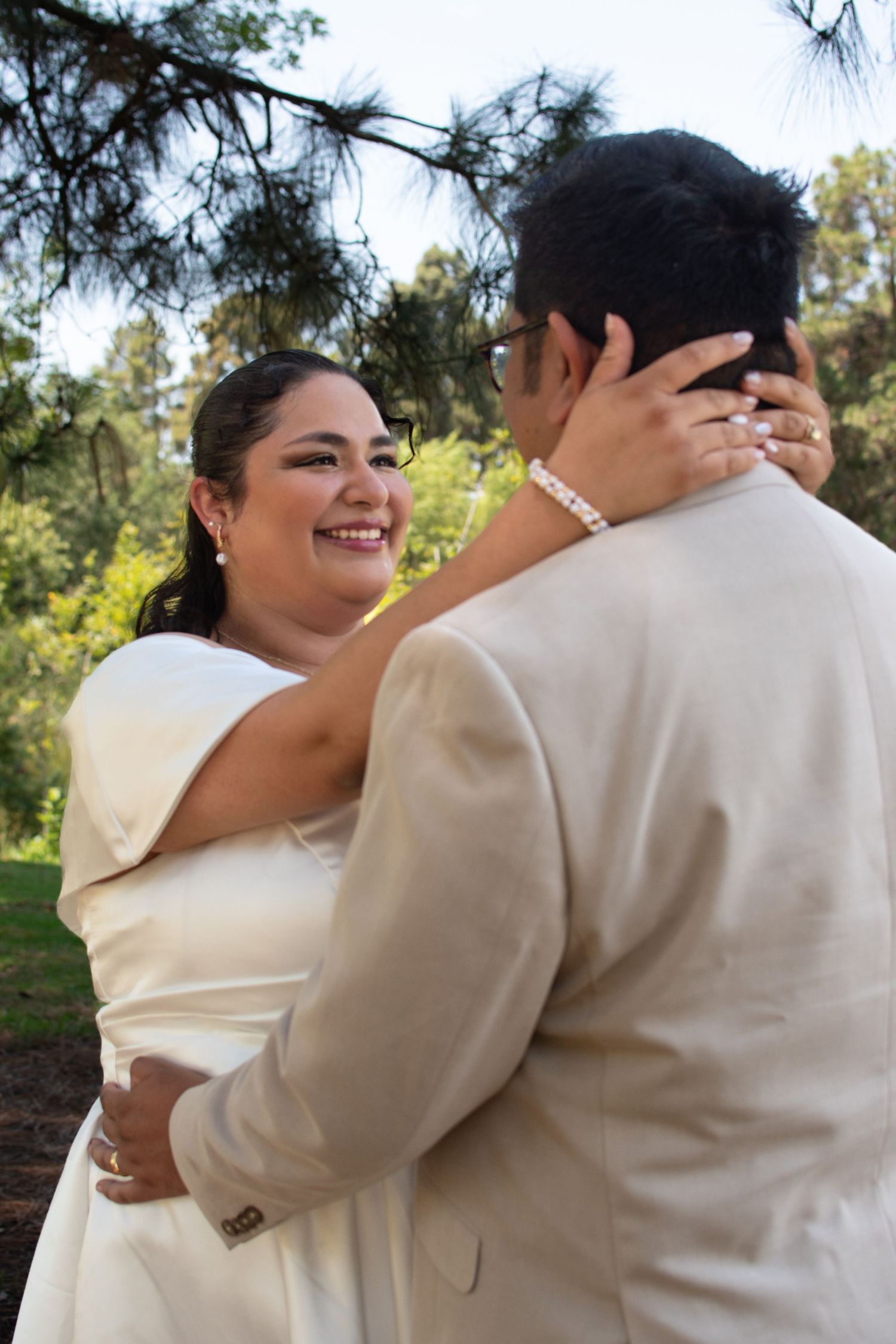 Joyful newlywed couple sharing an intimate moment outdoors with pine trees in the background.