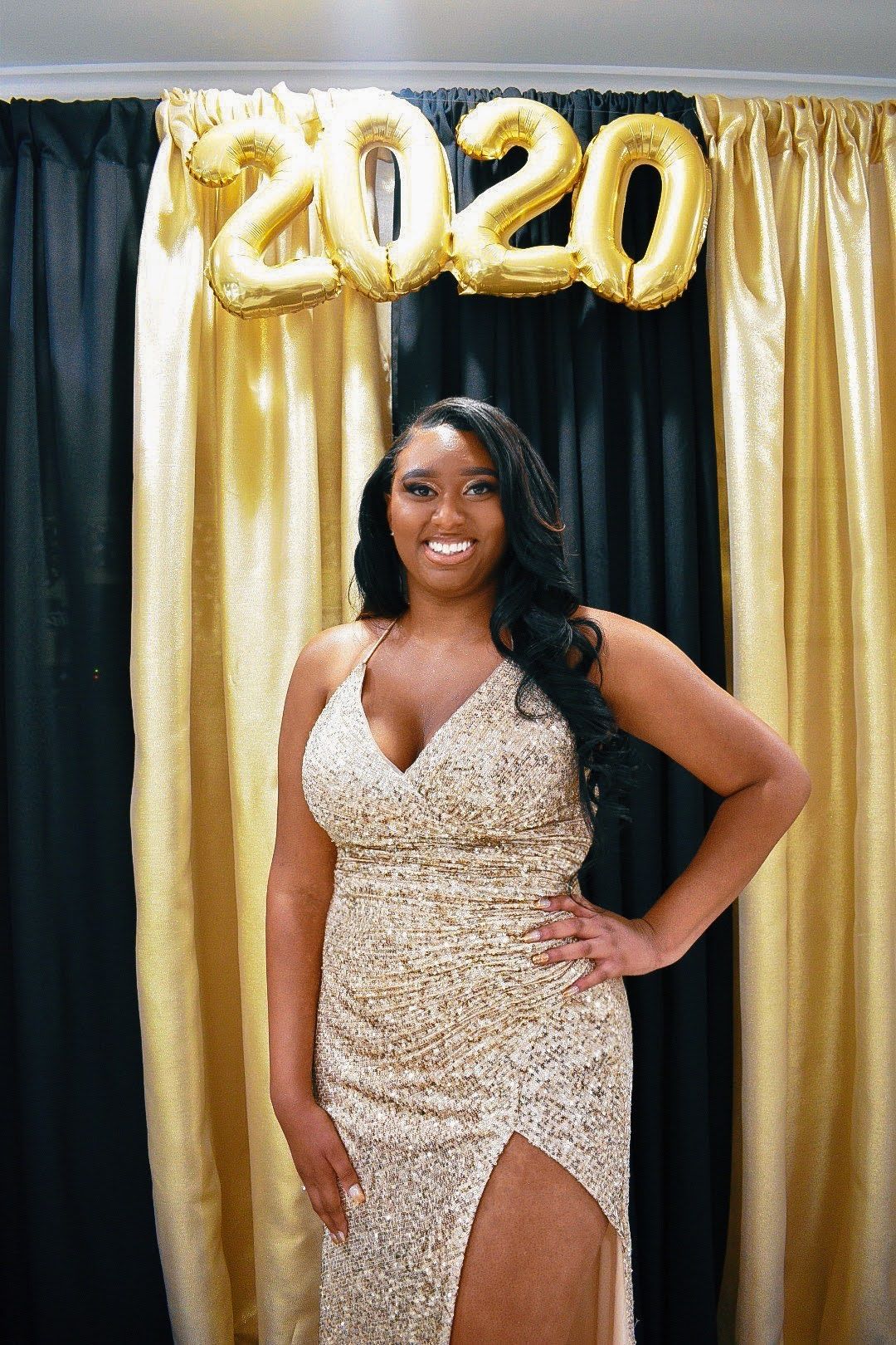 Prom celebration photo with 2020 balloon decor and fitted sequin formal dress.