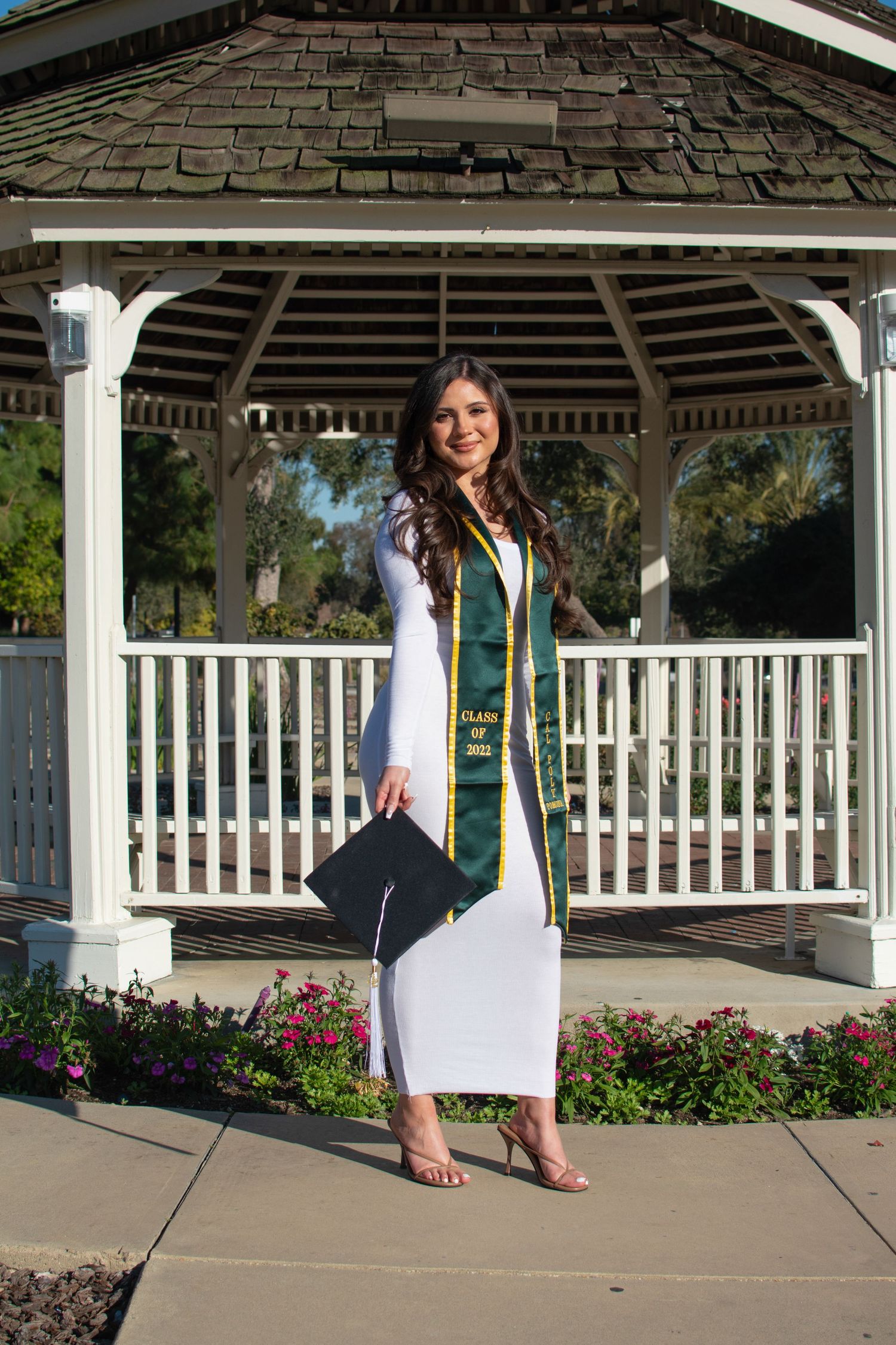 Graduation photo series showing poses in white dress and green stole under gazebo.