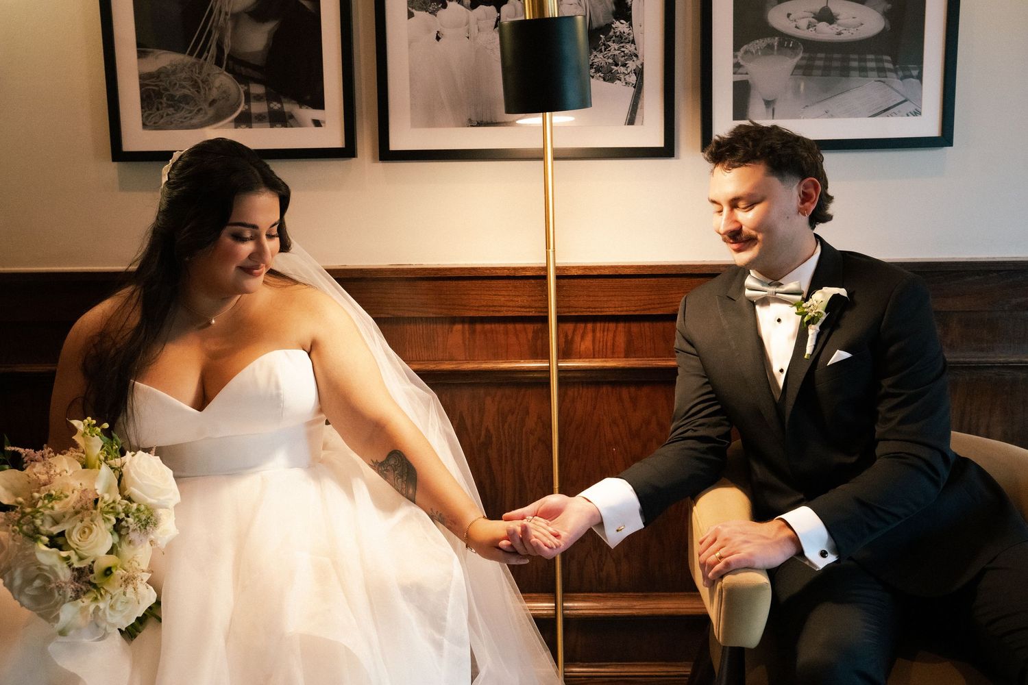 Bride and groom holding hands tenderly while seated together on their wedding day.