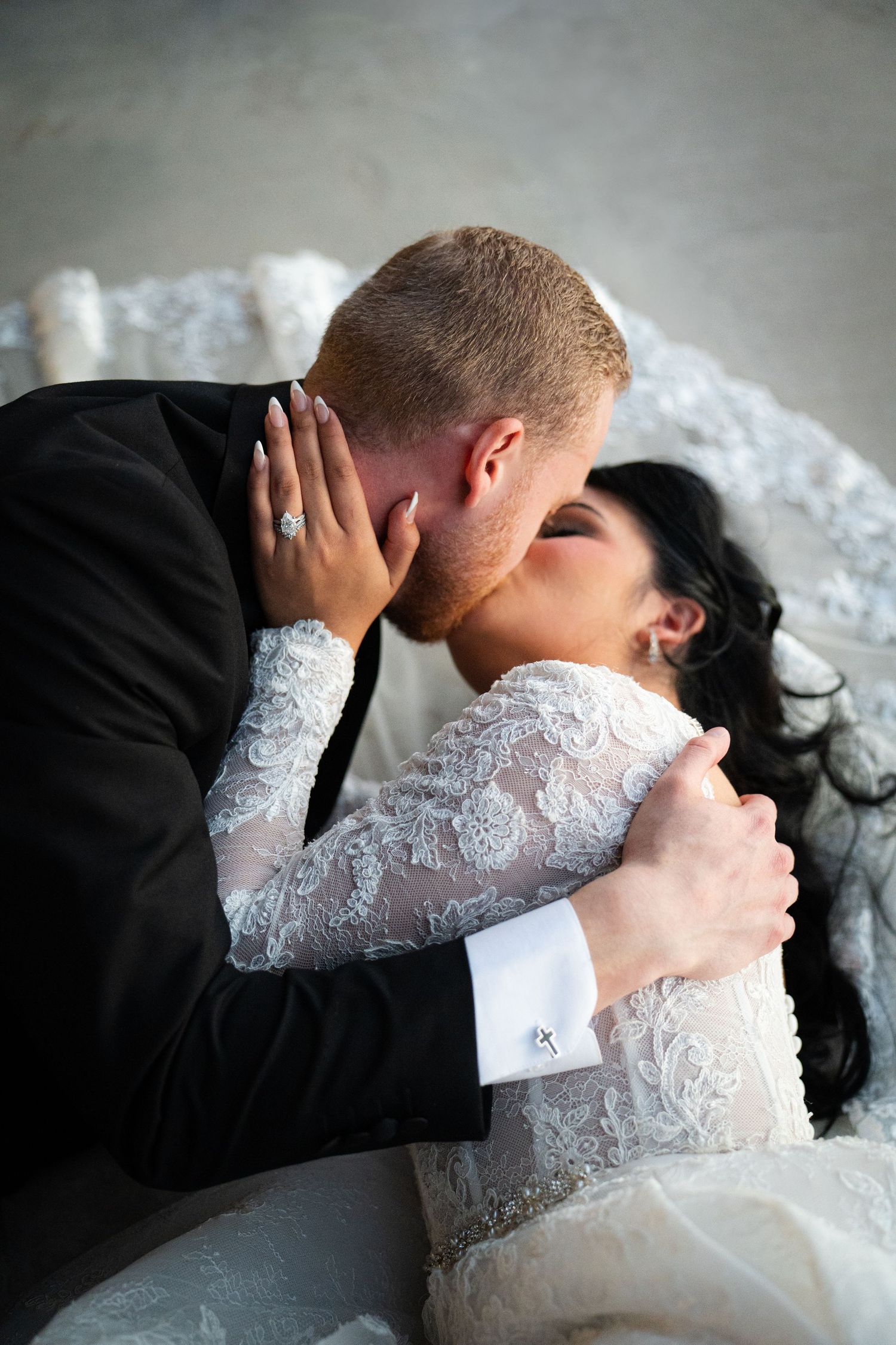Bride and groom sharing a passionate kiss in a romantic indoor wedding portrait.