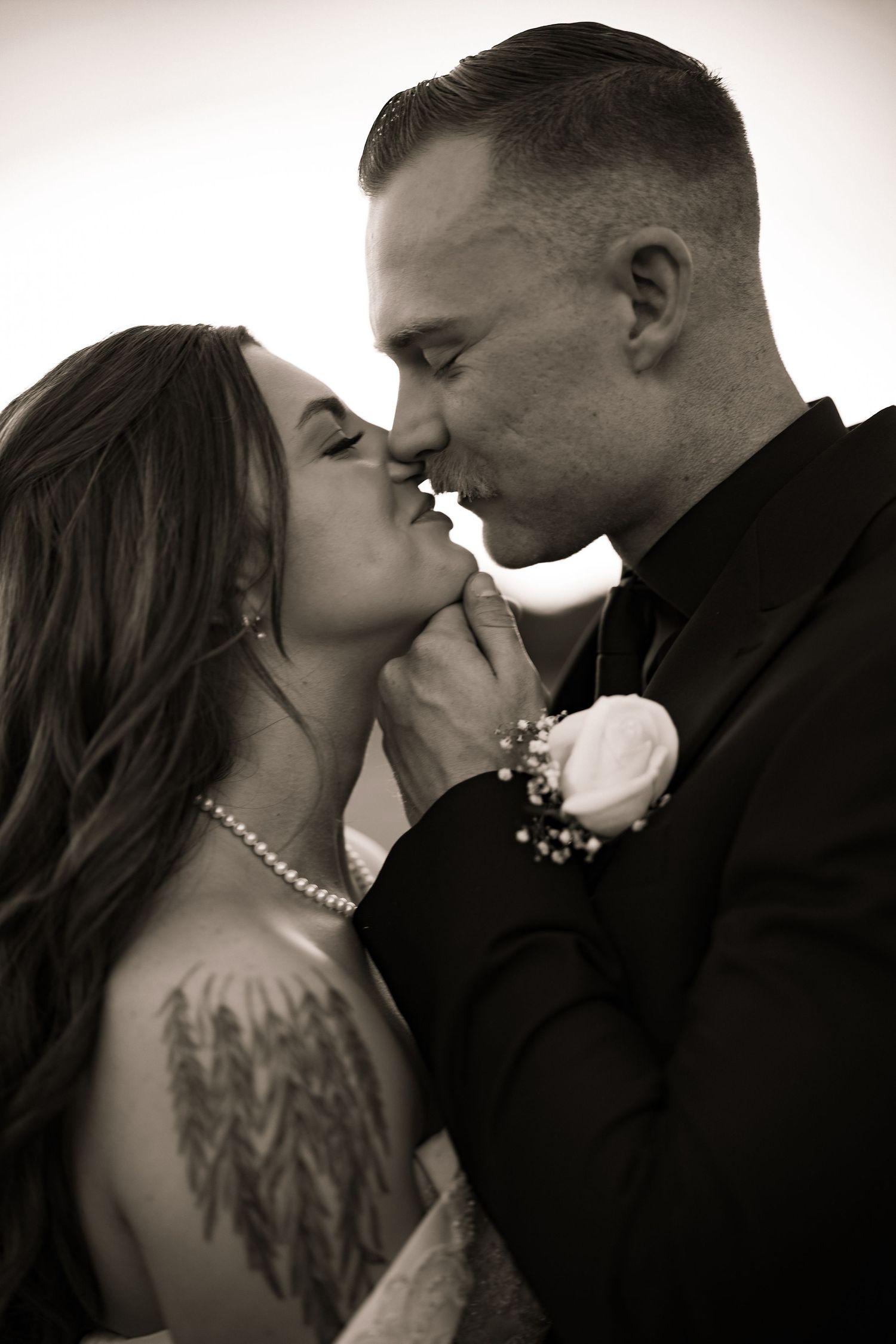 Black and white photo of bride and groom sharing a romantic kiss on their wedding day.