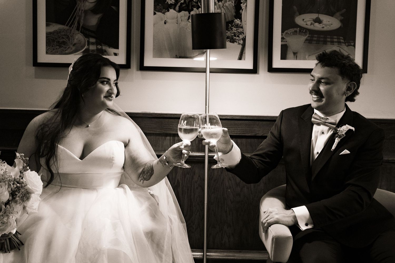 Bride and groom toasting with wine glasses in a black and white wedding portrait.