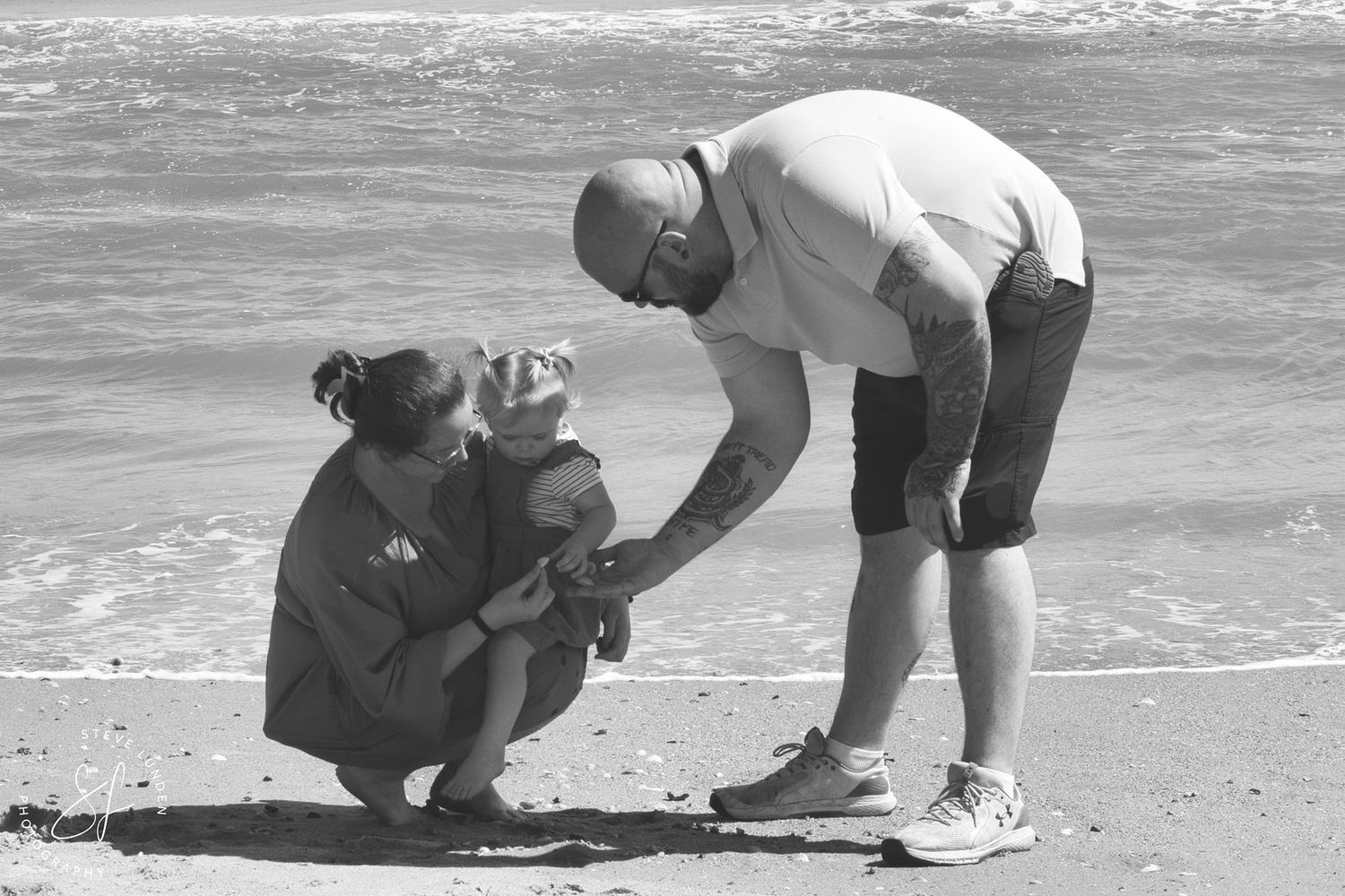 couple posing with daughter in front of ocean