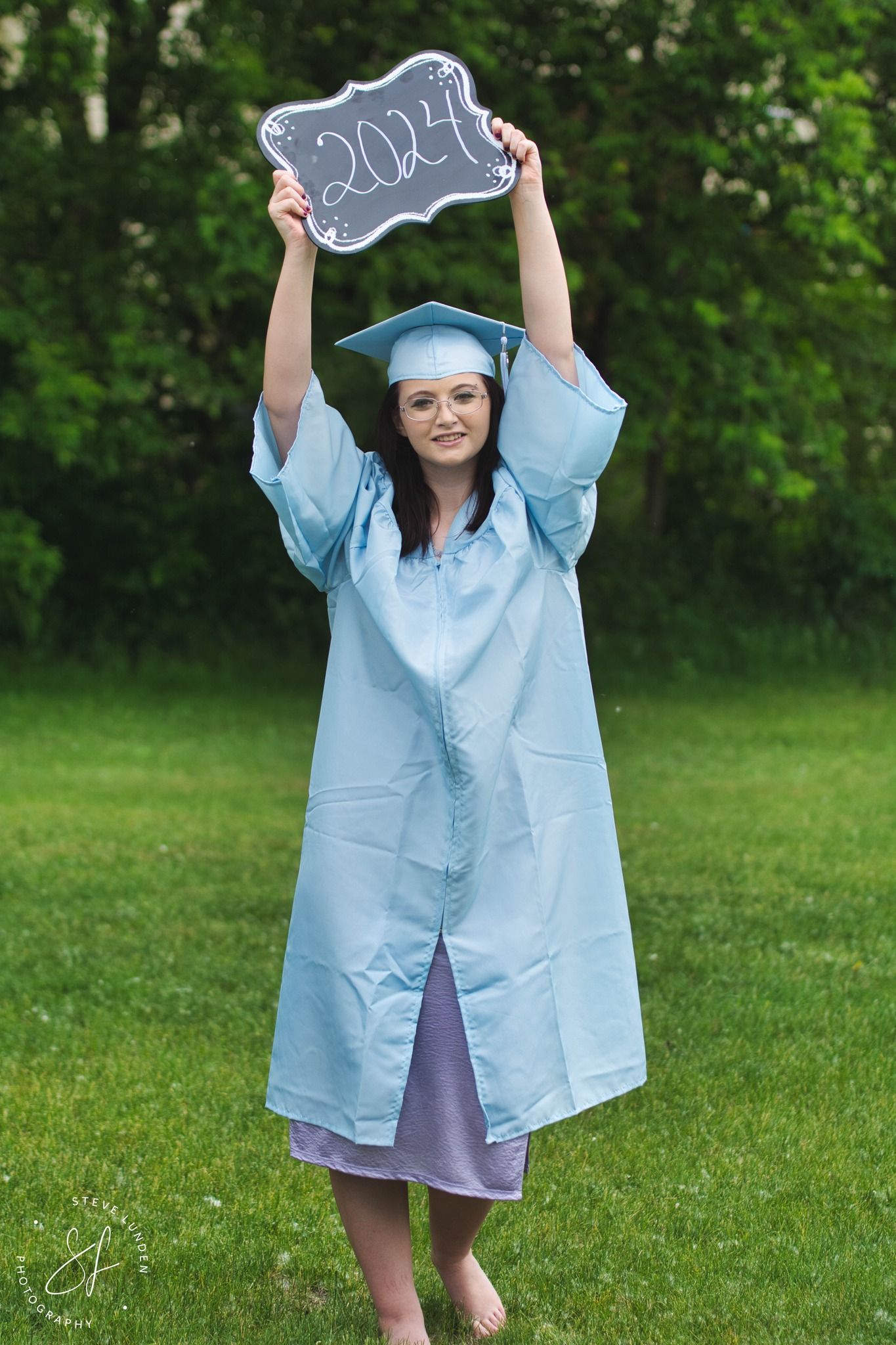 teenage graduate holding sign