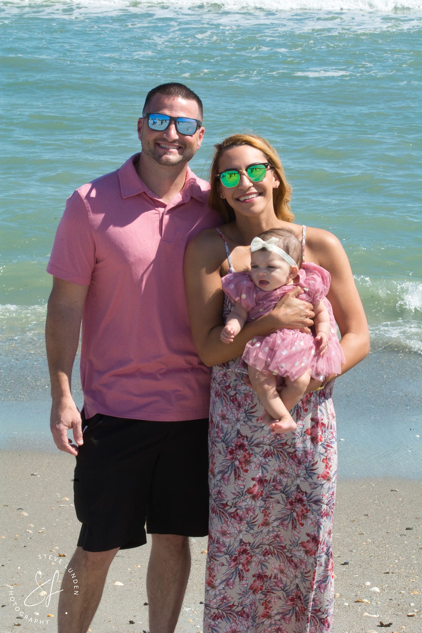couple and infant posing on beach in front of ocean