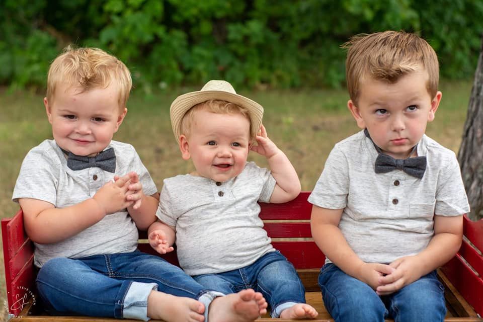 3 young children posing while sitting in a red wagon