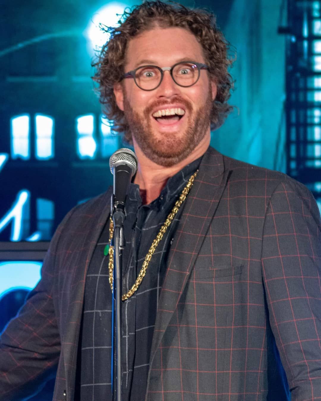 male comedian on stage making a surprised face