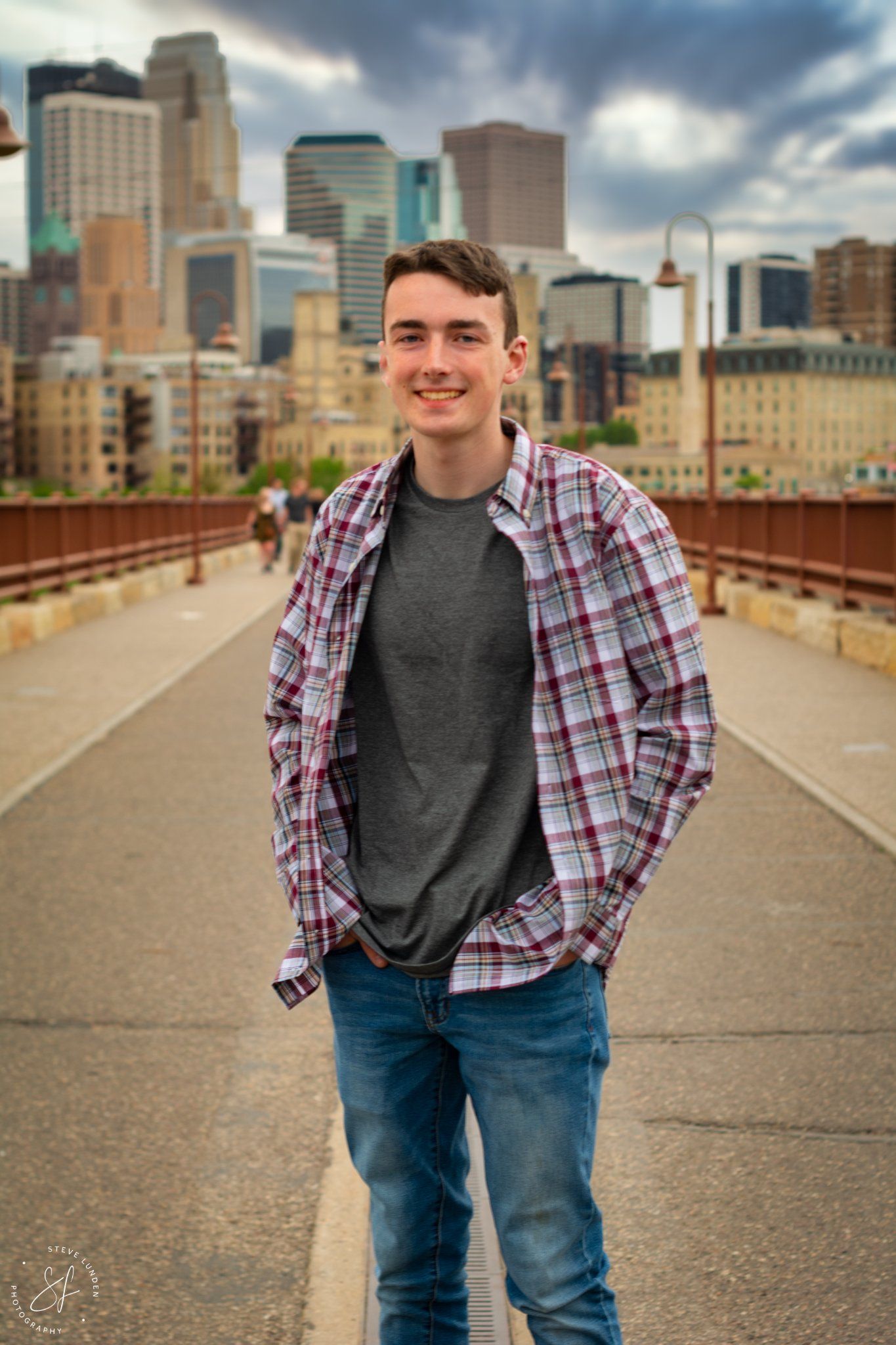 high school senior boy posing in front of minneapolis skyline