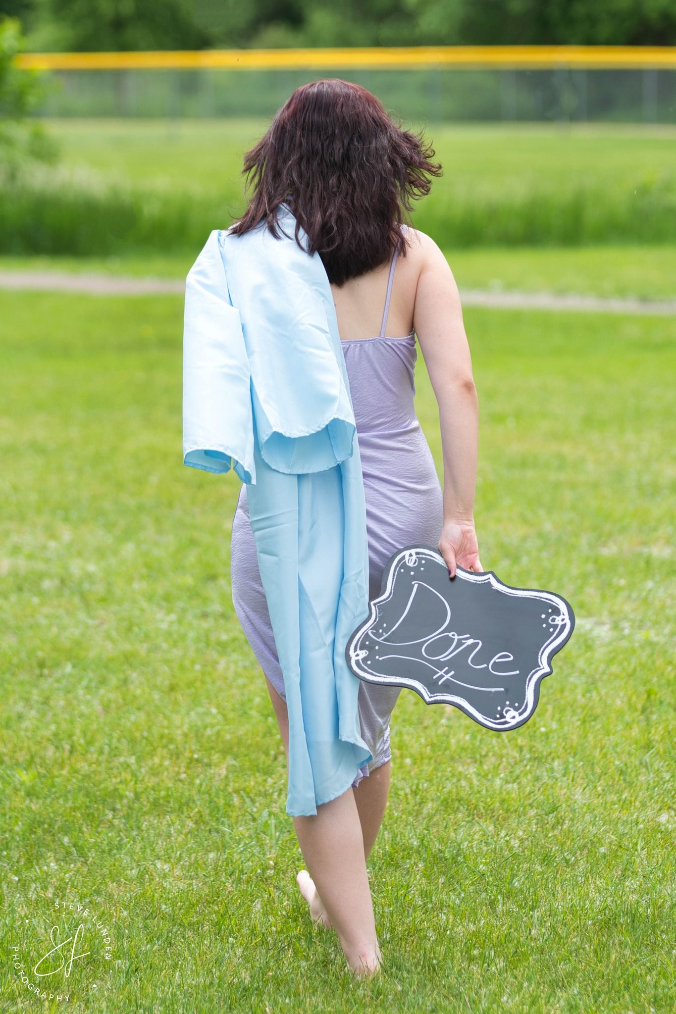 high school graduate walking away with gown over shoulder