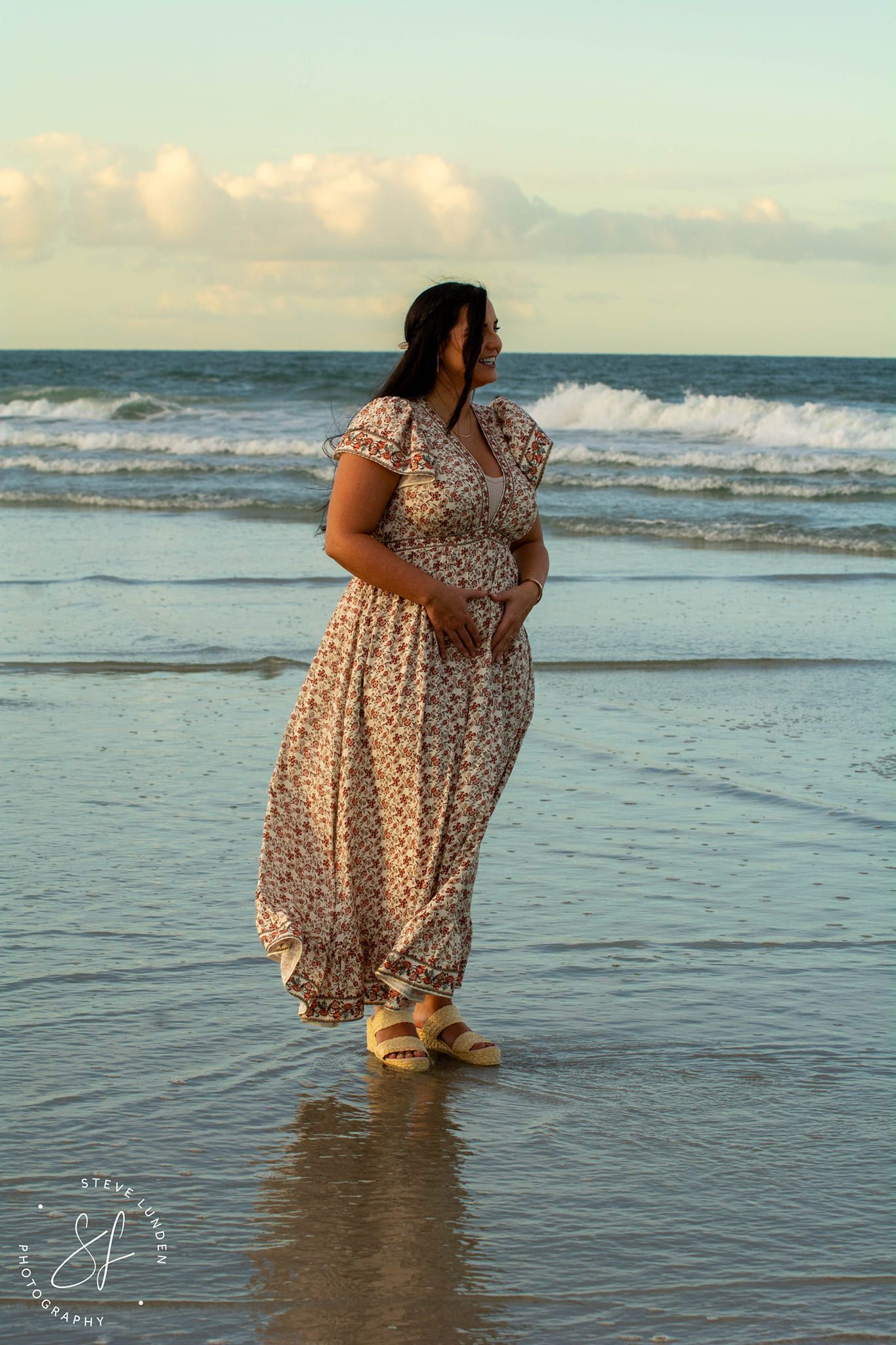 young woman posing with new pregnancy by ocean