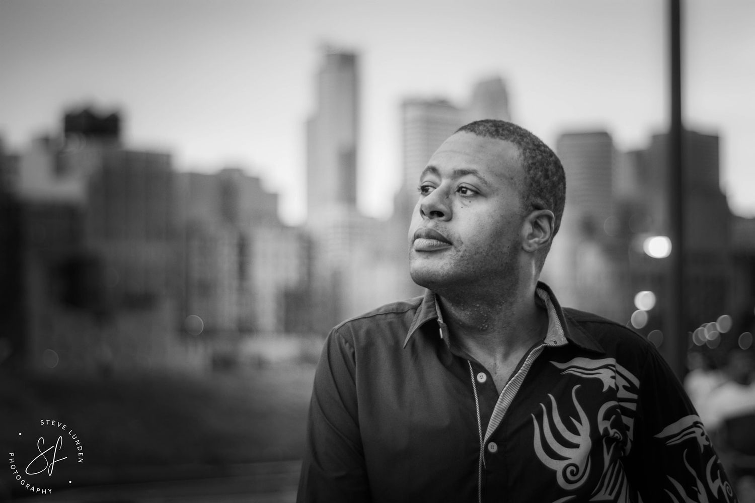 black and white of man posing in front of minneapolis skyline