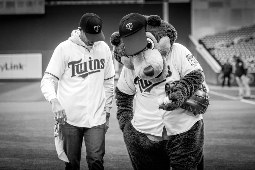 black and white image of male walking with Twins mascot