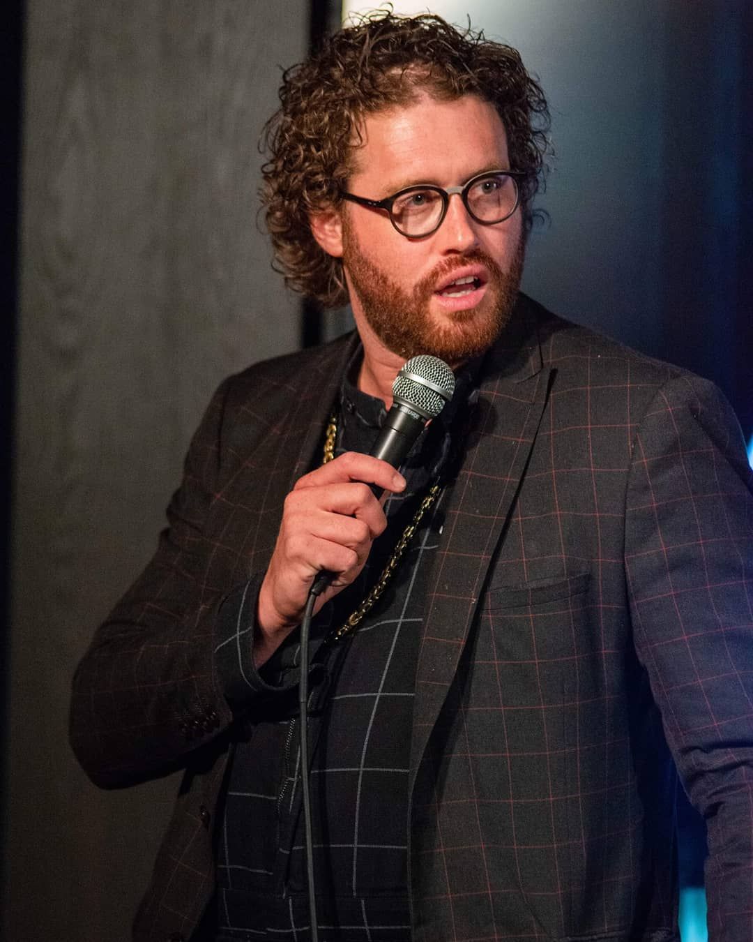 male comedian on stage looking to the side
