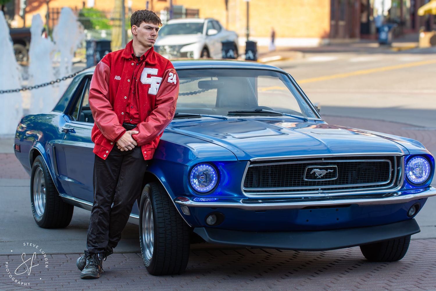 teenage boy posing on side of blue sportscar