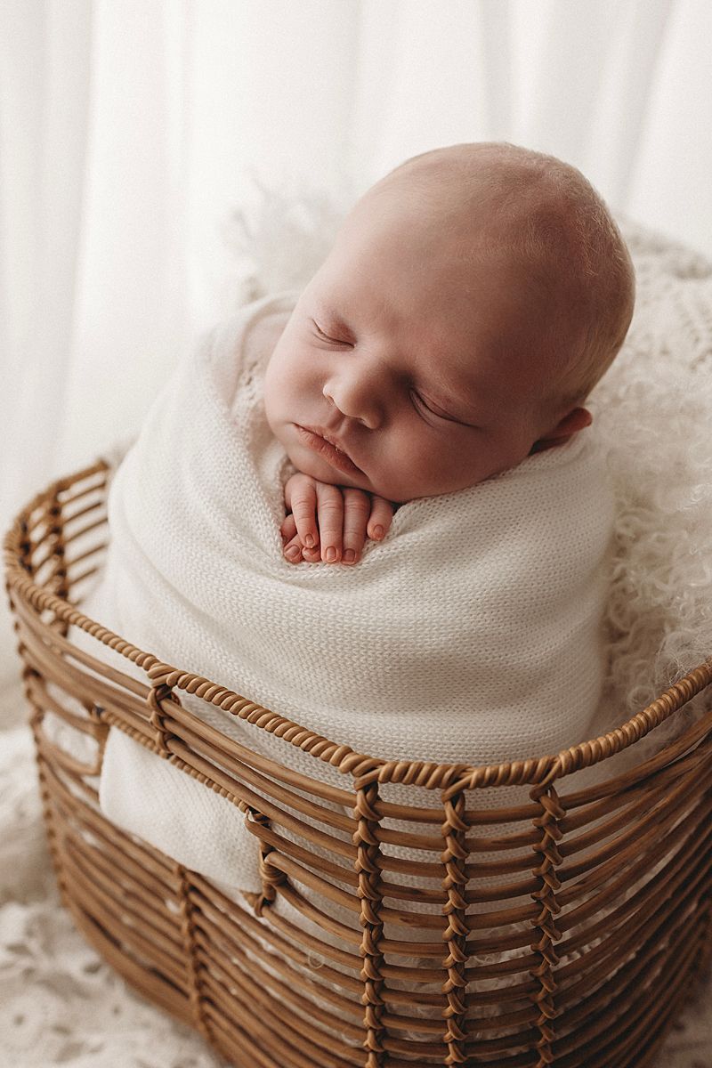 newborn baby girl posed like potato sack in wicker basket during photoshoot in geelong