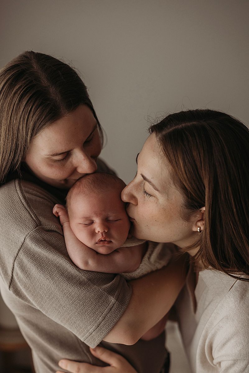 newborn baby girl snuggled in. ums arms, sleeping in timeless pose