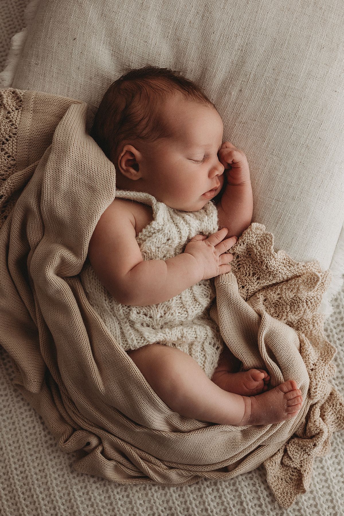posing newborns during photoshoot, sleeping in brown knit blanket