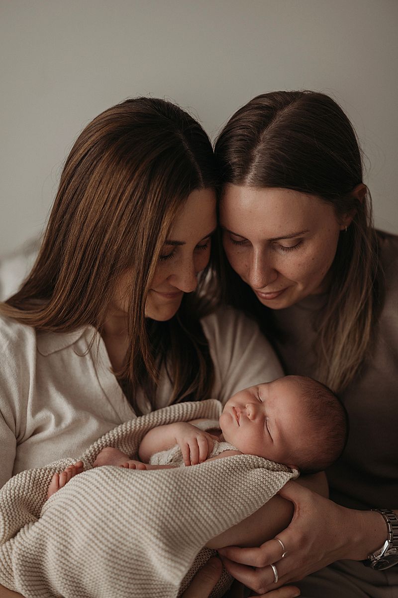 two mums holding their new baby, after years of waiting and trying for baby