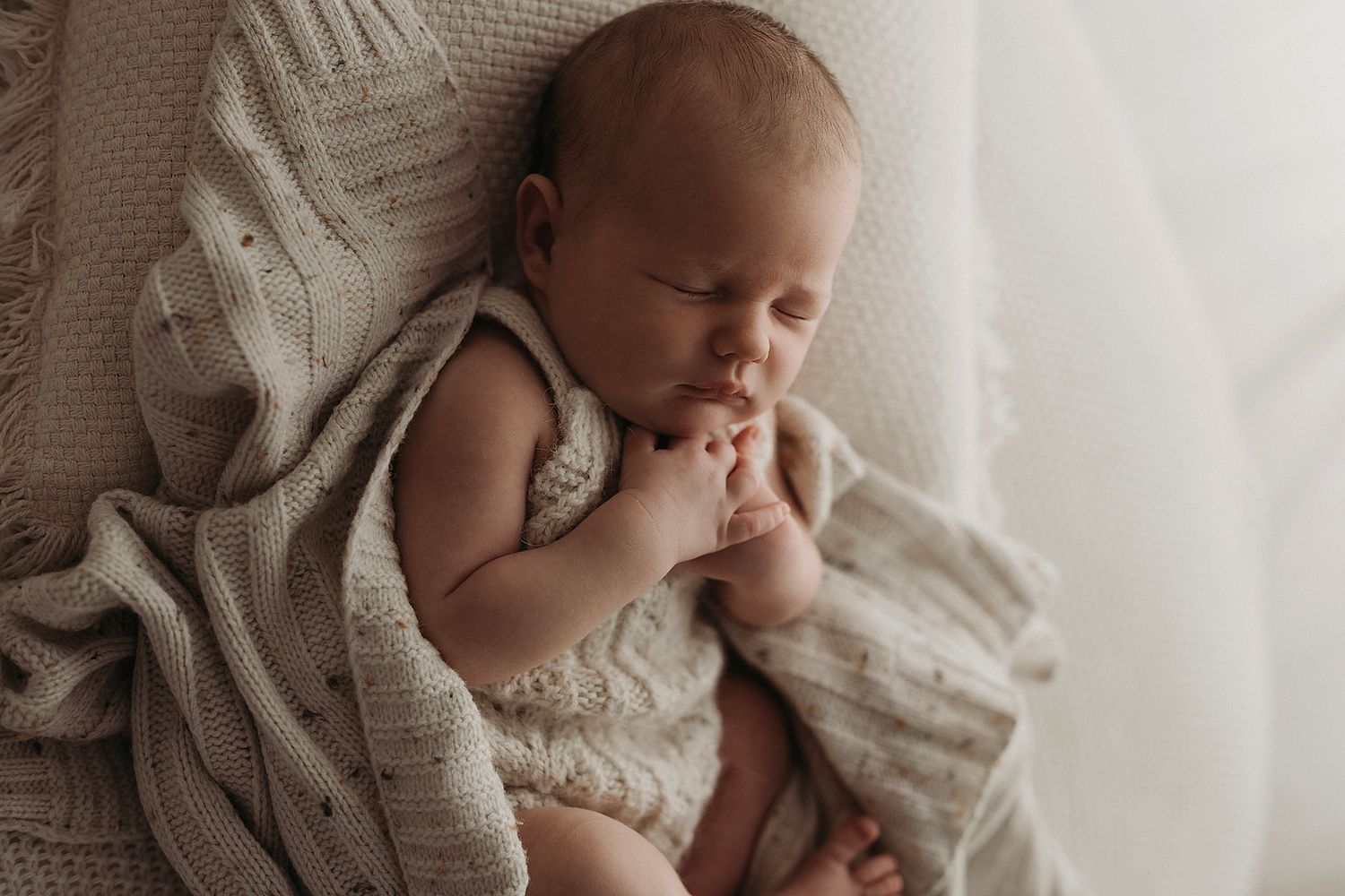 newborn baby girl sleeping soundly in a cream knit handmade romper