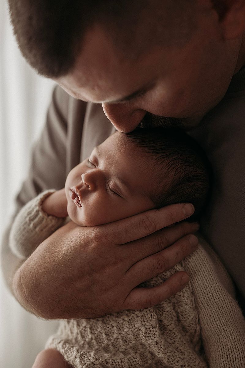 newborn baby boy sleeping in dads arms, cosy and loved for his newborn photography session