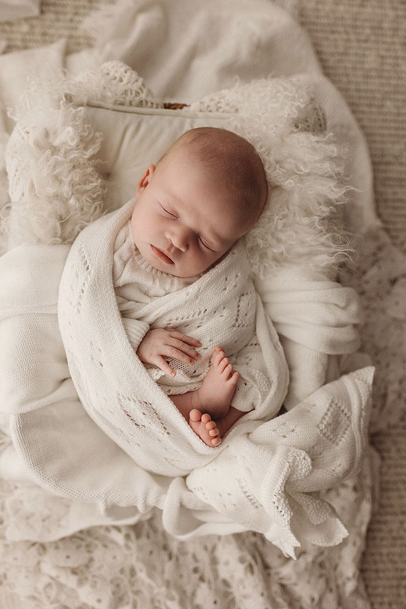 newborn baby girl swaddled in white blankets posed in a newborn photography studio geelong
