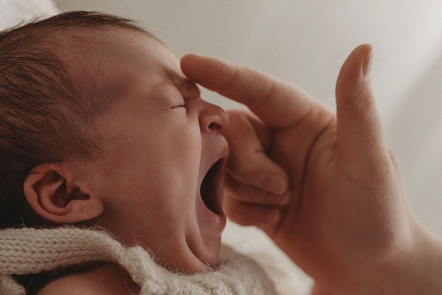 sleepy newborn yawns with mums touch, capturing moments that matter