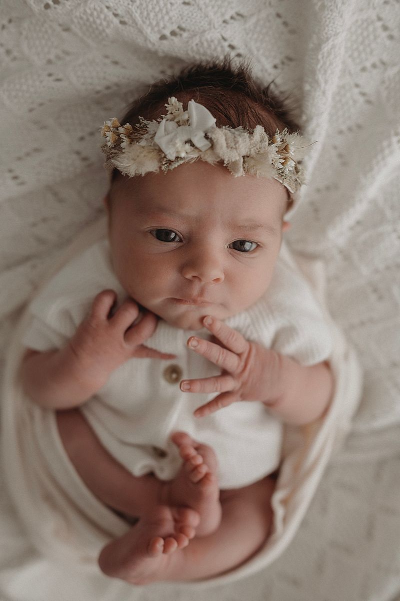 awake newborn girl wearing floral headband, not sleeping during photoshoot in geelong