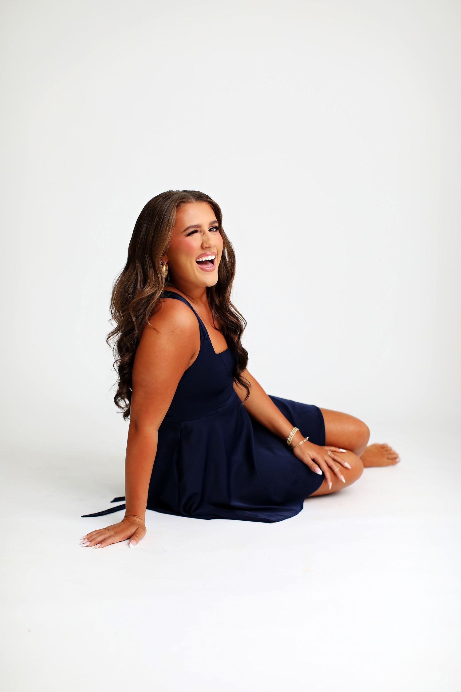 Elegant poses in navy dress during studio photoshoot on white background.