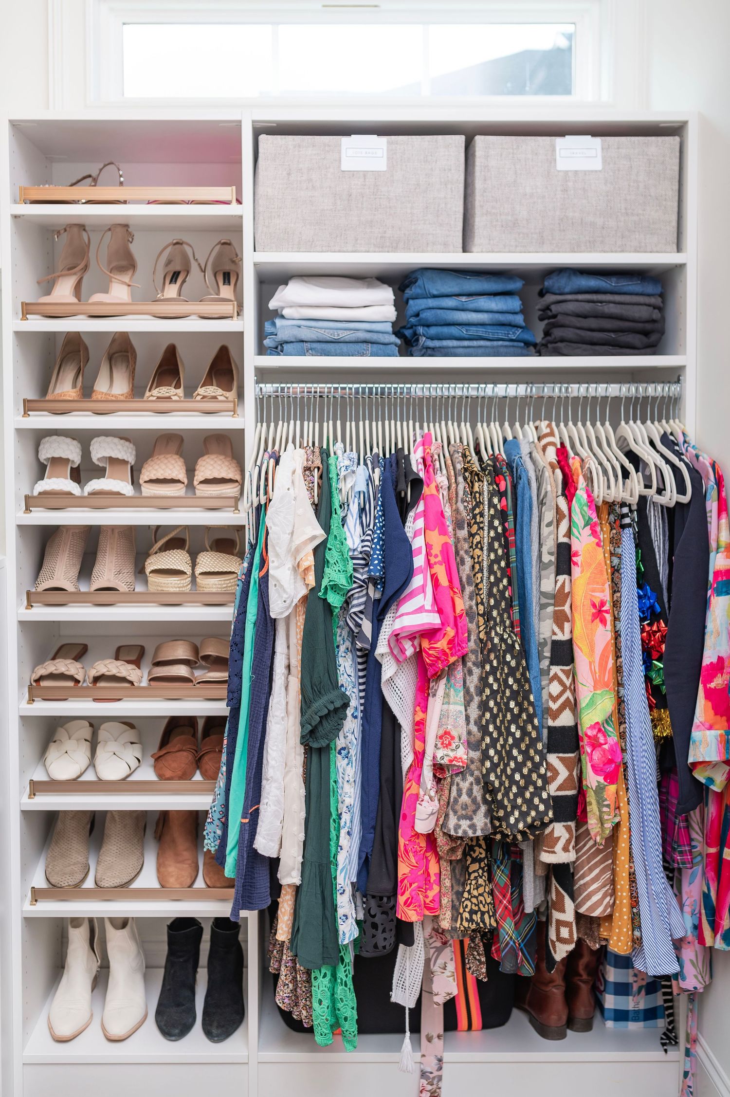 Organized closet featuring colorful dresses, folded denim, storage boxes, and tiered shoe shelves with neutral footwear.