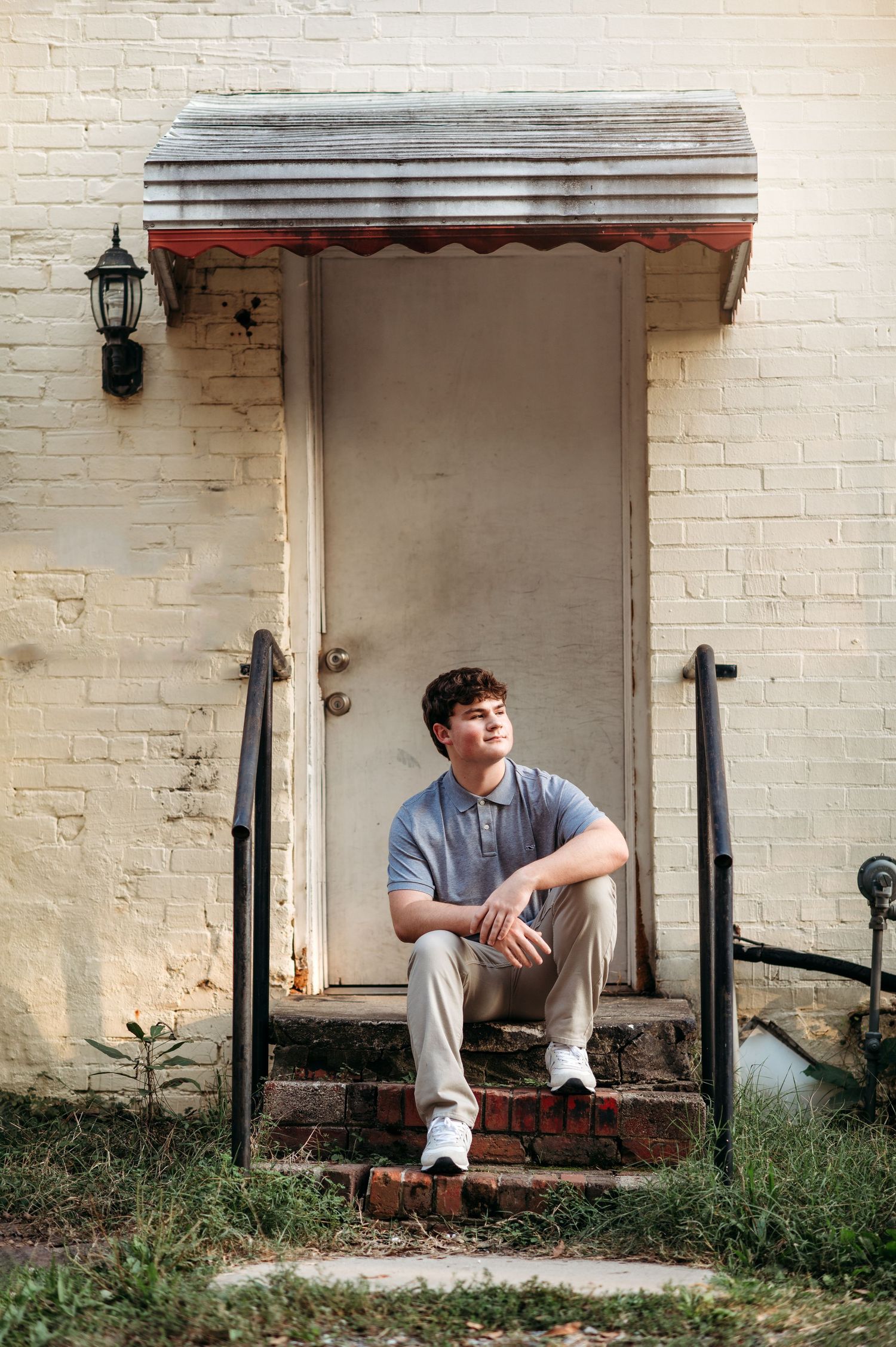 Student sits casually on brick steps during outdoor portrait session.