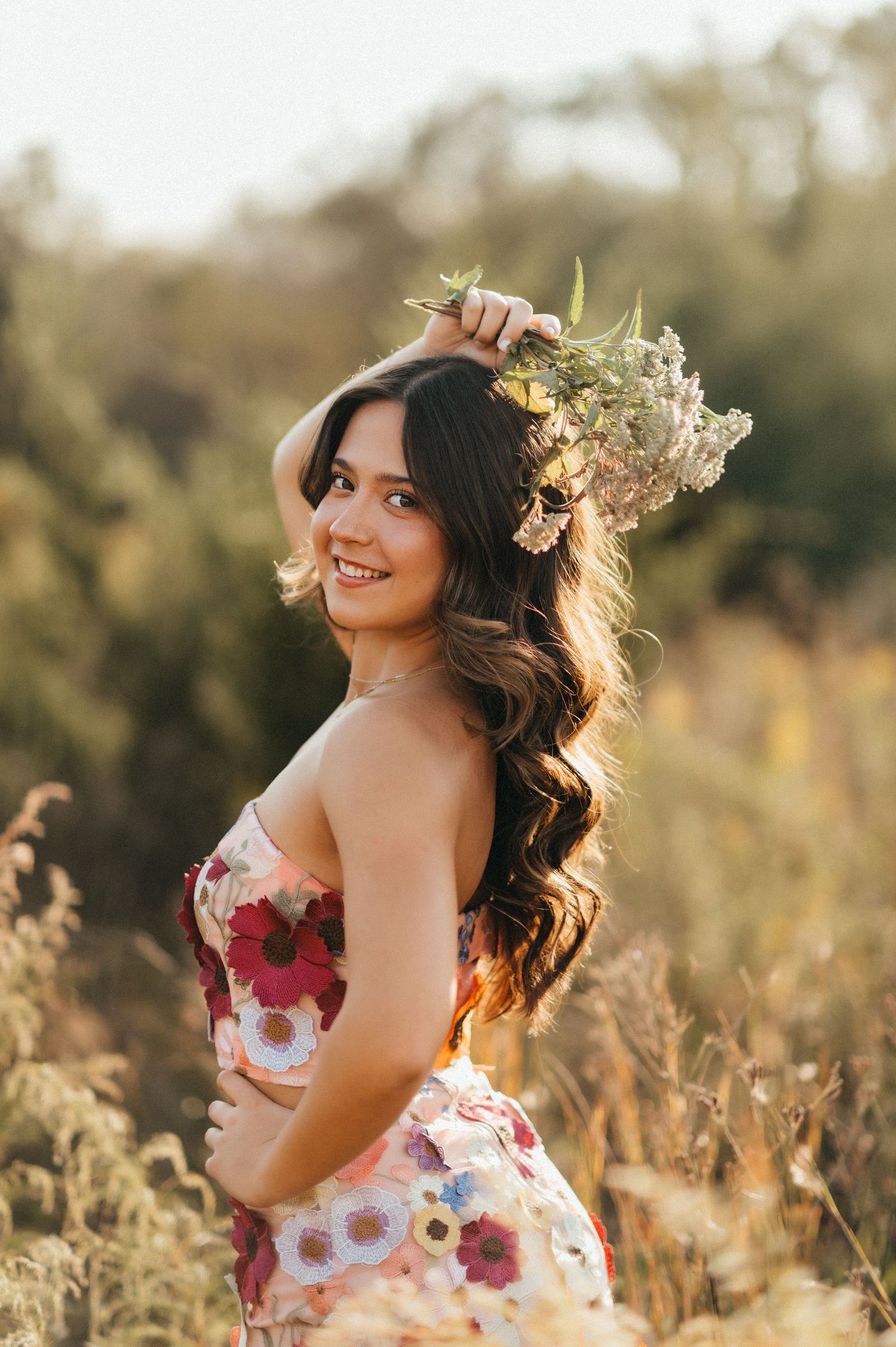 Floral dress portrait in sunlit field with golden backlighting.