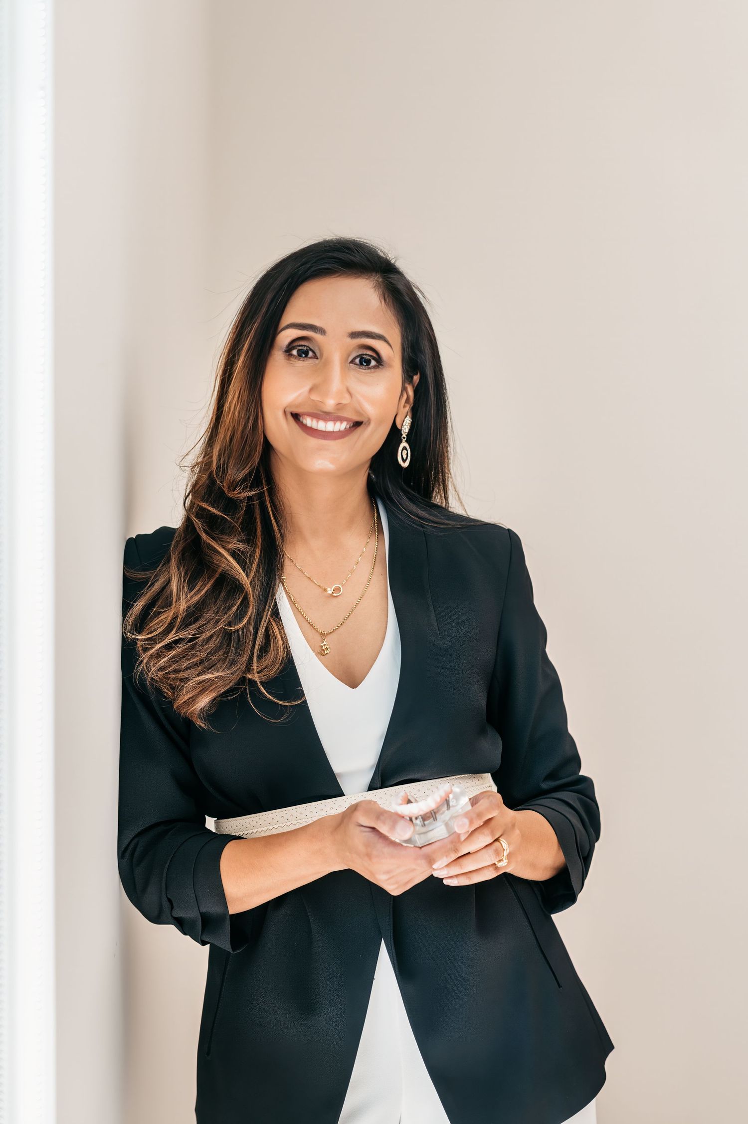 Woman in black blazer and white shirt smiles expressively while posing for a sequence of professional photos.