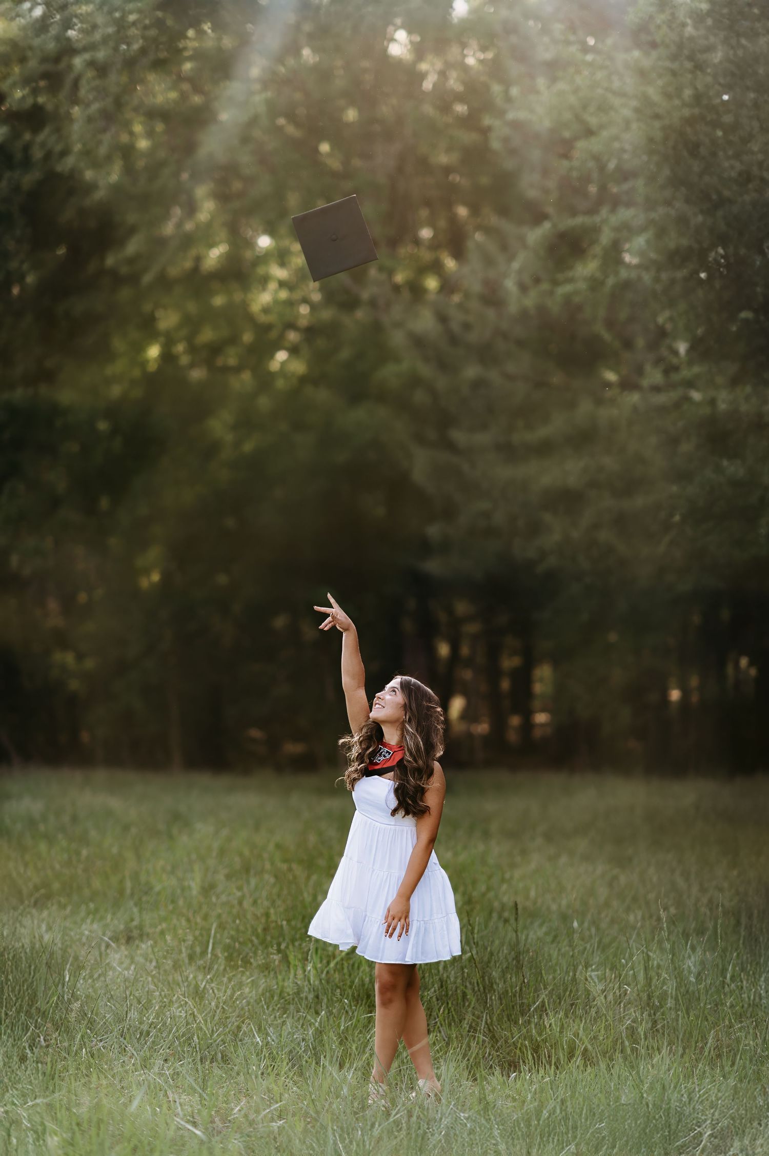 White dress twirls in a grassy field during golden hour photography session.