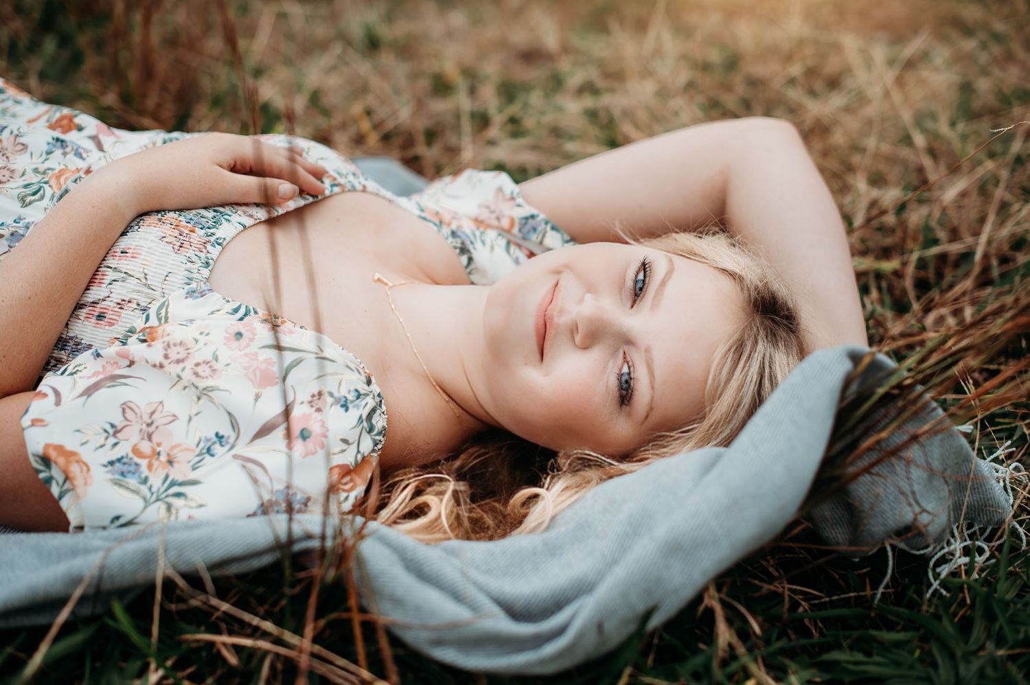 Natural light portrait series lying in grass wearing floral print dress.