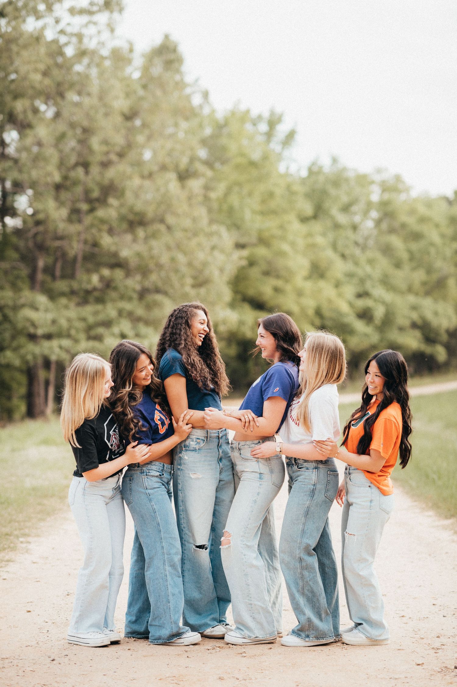 Group of friends in denim jeans laughing and bonding together on a nature trail.