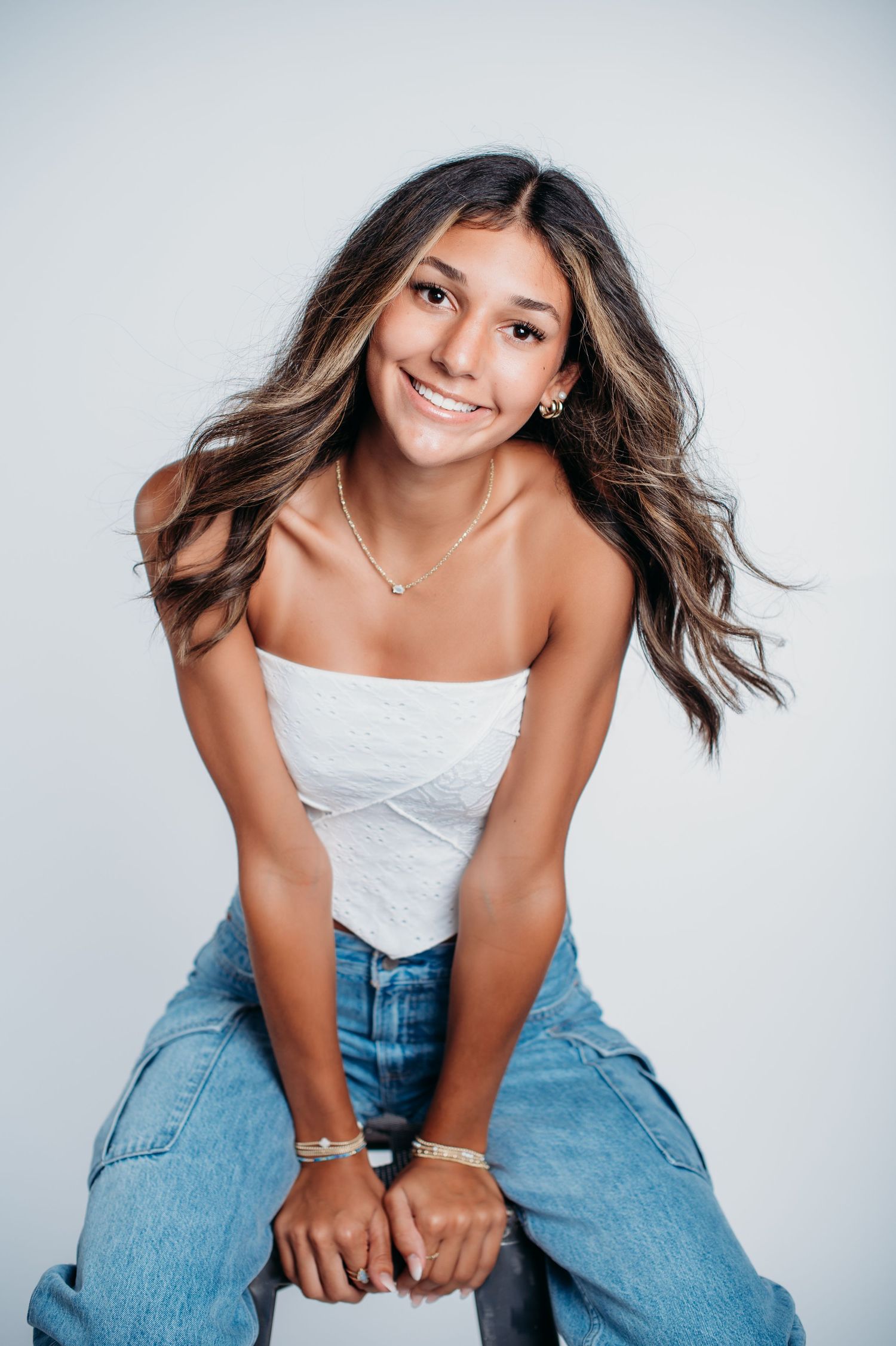 Studio portrait in casual denim and white top with flowing hair against light background.