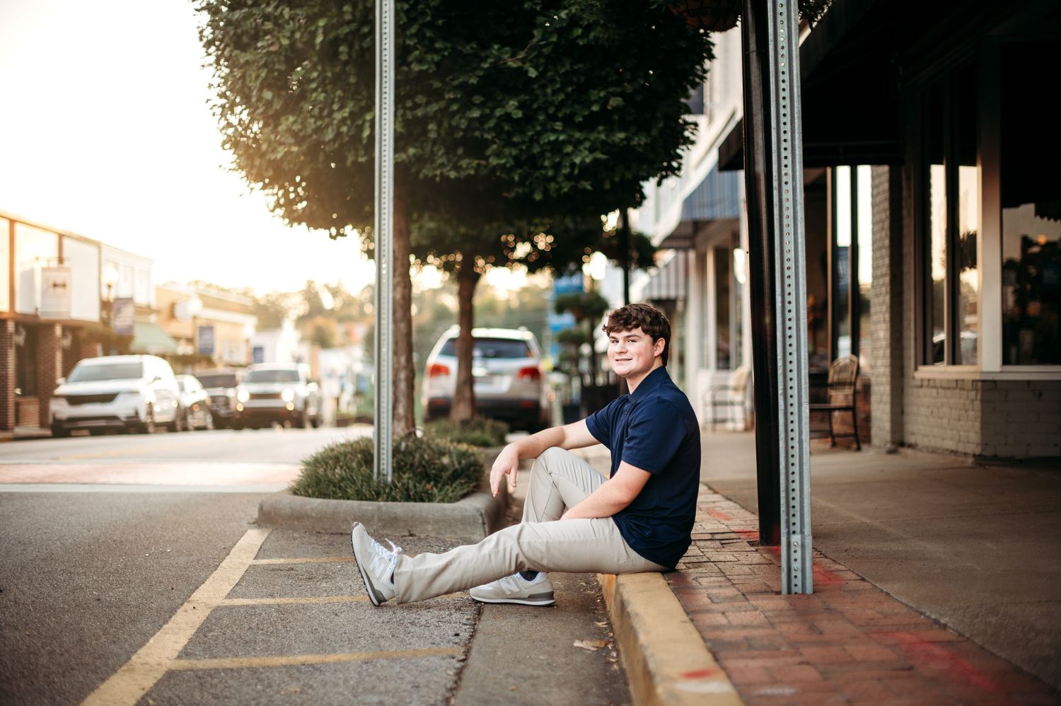 Casual senior portrait session against urban storefront backdrop at sunset.