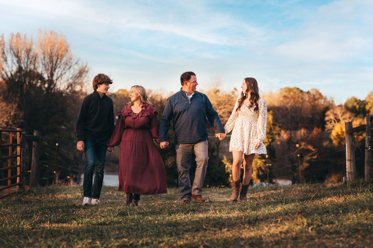A group walks together on a hillside trail during golden hour with autumn trees in the background.