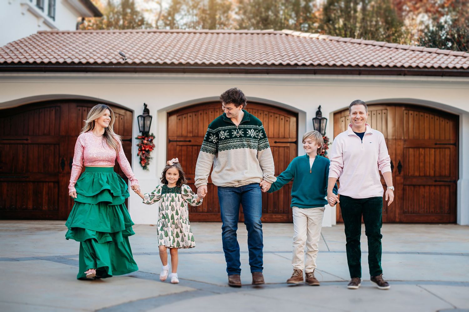 Group in coordinating green and white outfits standing in front of Spanish style wooden garage doors at sunset.