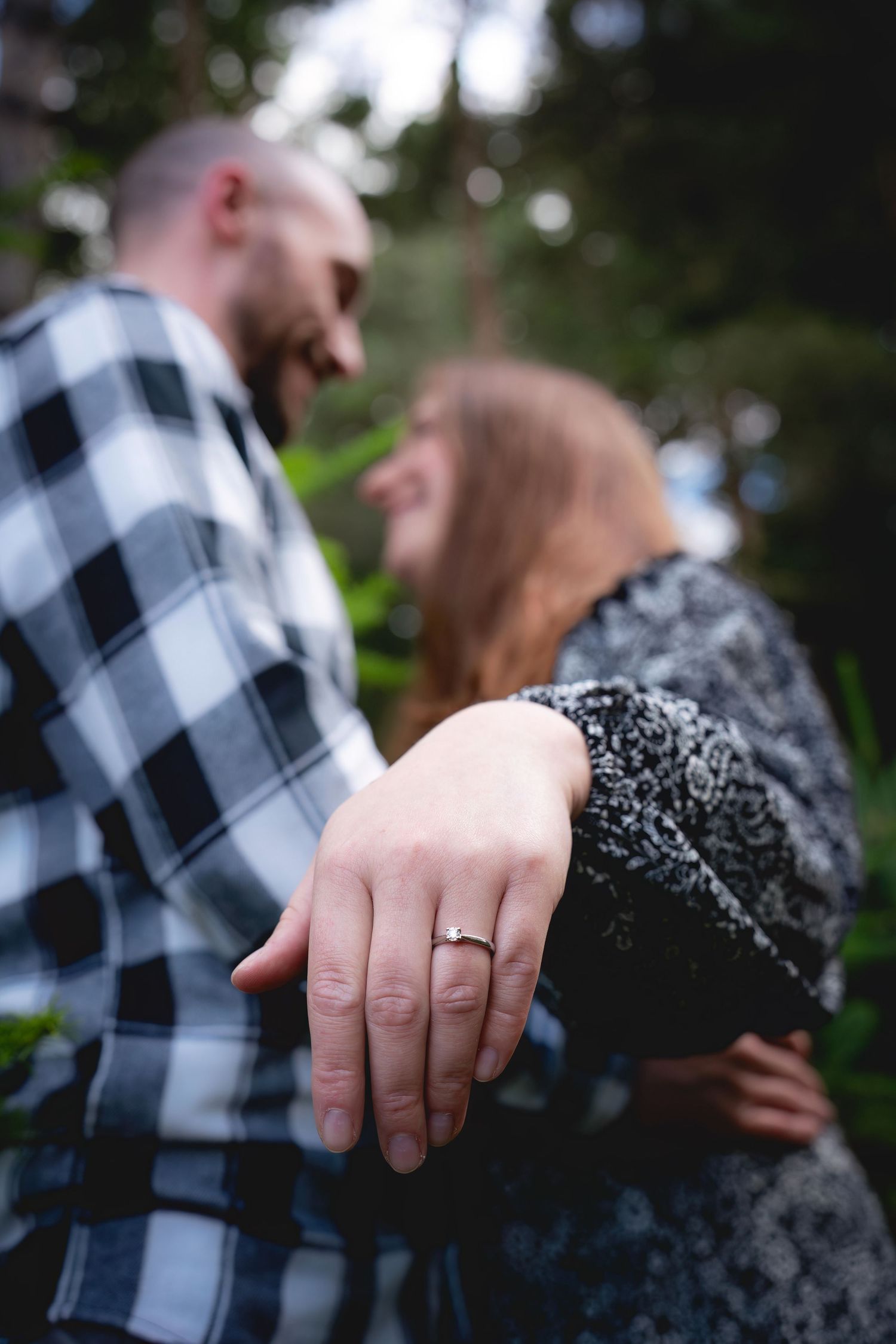 A series of engagement photos showing off a wedding ring while the couple embraces in a black and white flannel shirt setting.