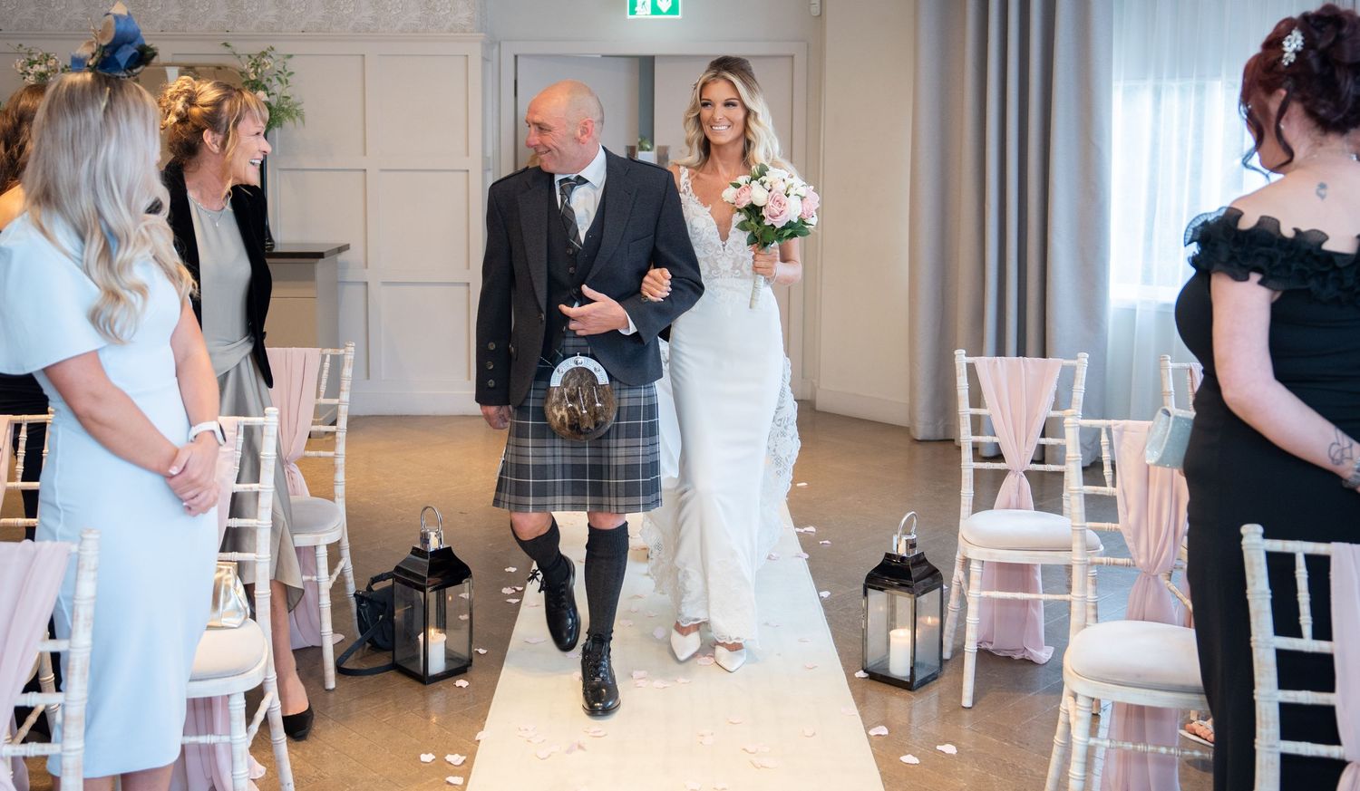 Modern wedding reception venue with white chairs and floral decorations.