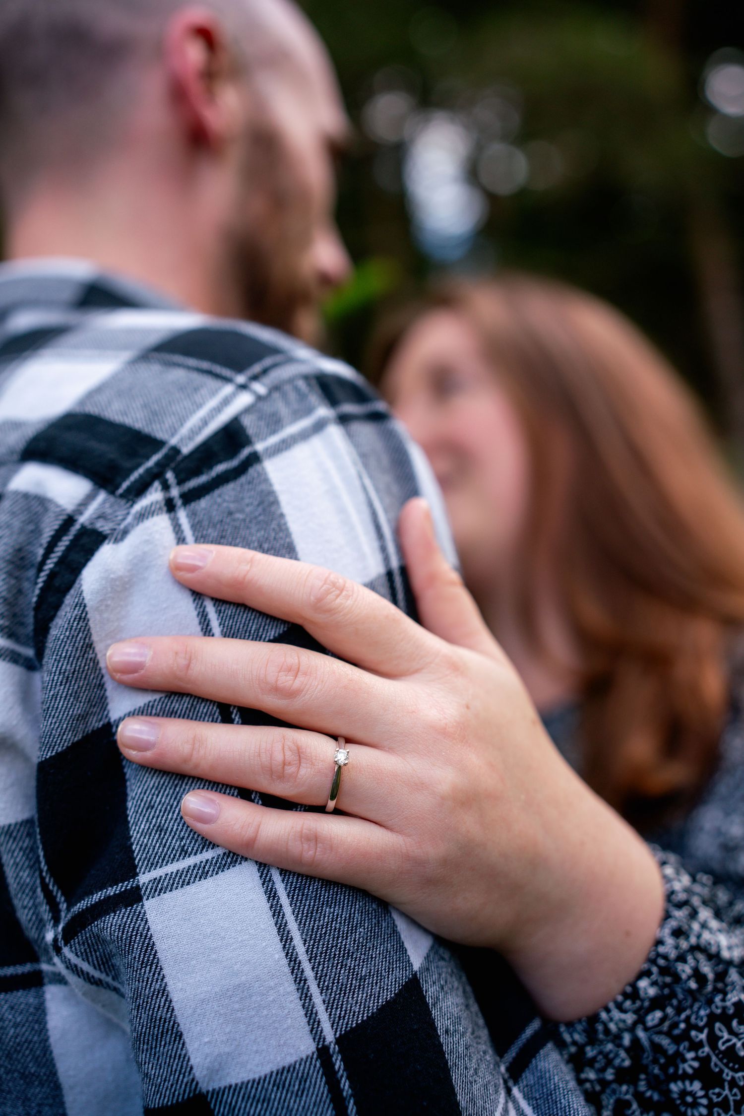 Close up series showing a wedding ring on a hand resting against a grey and black plaid fabric background.